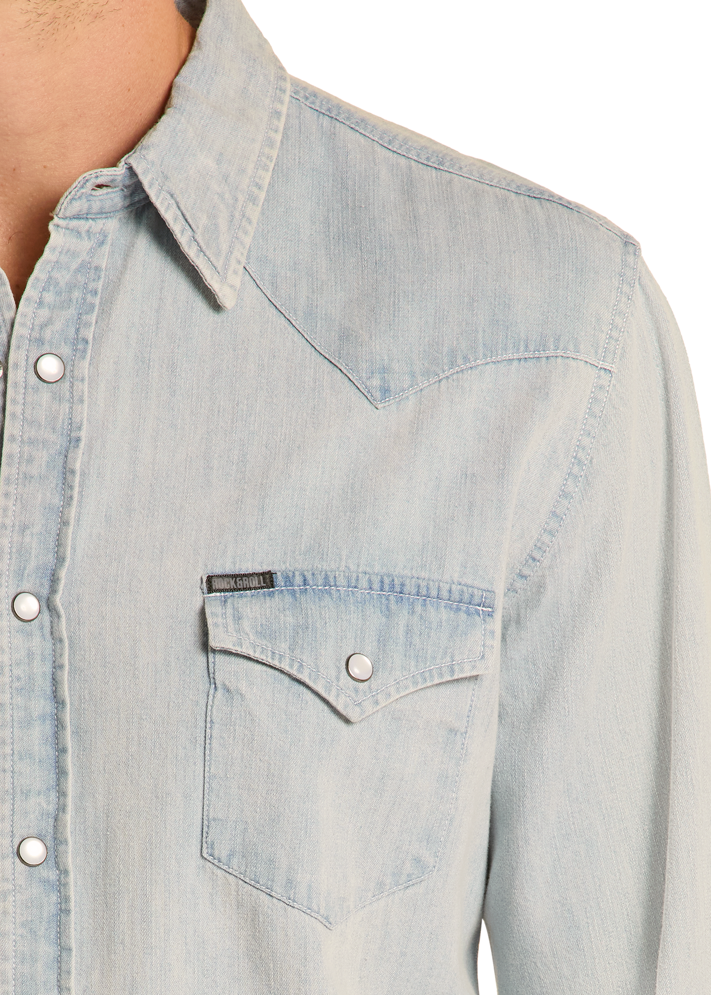 Close-up of a person wearing the Rock & Roll Denim Slim Fit Light Wash Denim Snap Shirt, featuring metal snap buttons, a pointed collar, and a chest pocket with flap and button closure. Upper torso only is visible. The slim fit gives a modern look.