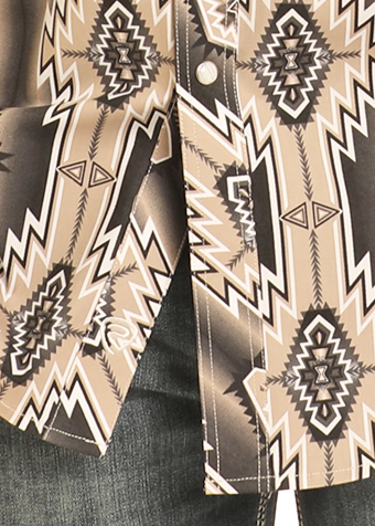 Close-up of the Rock & Roll Denim Slim Fit Tan Aztec Long Sleeve Snap Shirt, featuring a geometric southwestern pattern in beige, black, and white, metal snap buttons, and blue jeans partially visible below.