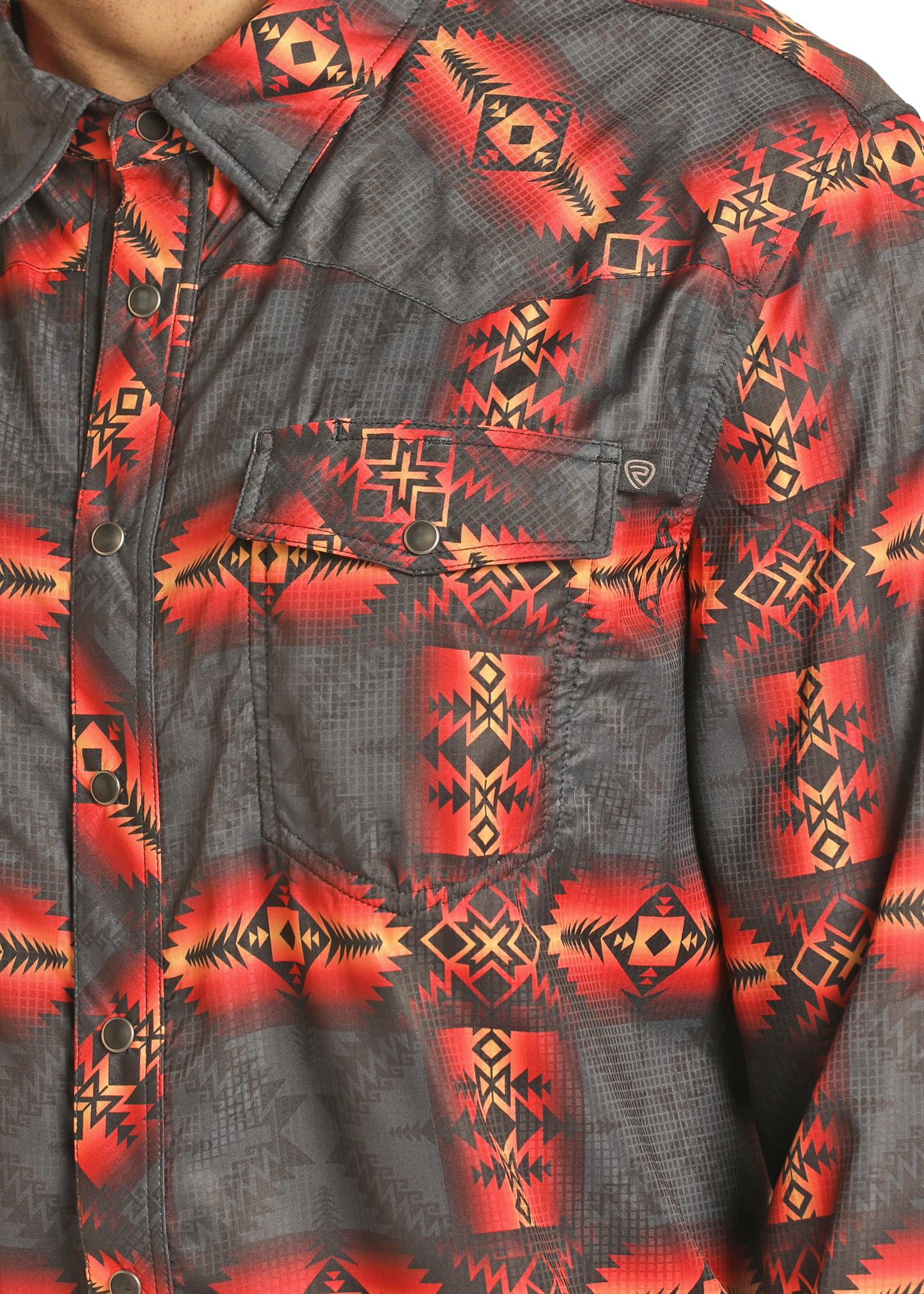 A close-up of the Rock & Roll Denim TEK Western Red Aztec Long Sleeve Shirt with a slim fit, bold red, orange, and black geometric pattern, and a front chest pocket with a buttoned flap.