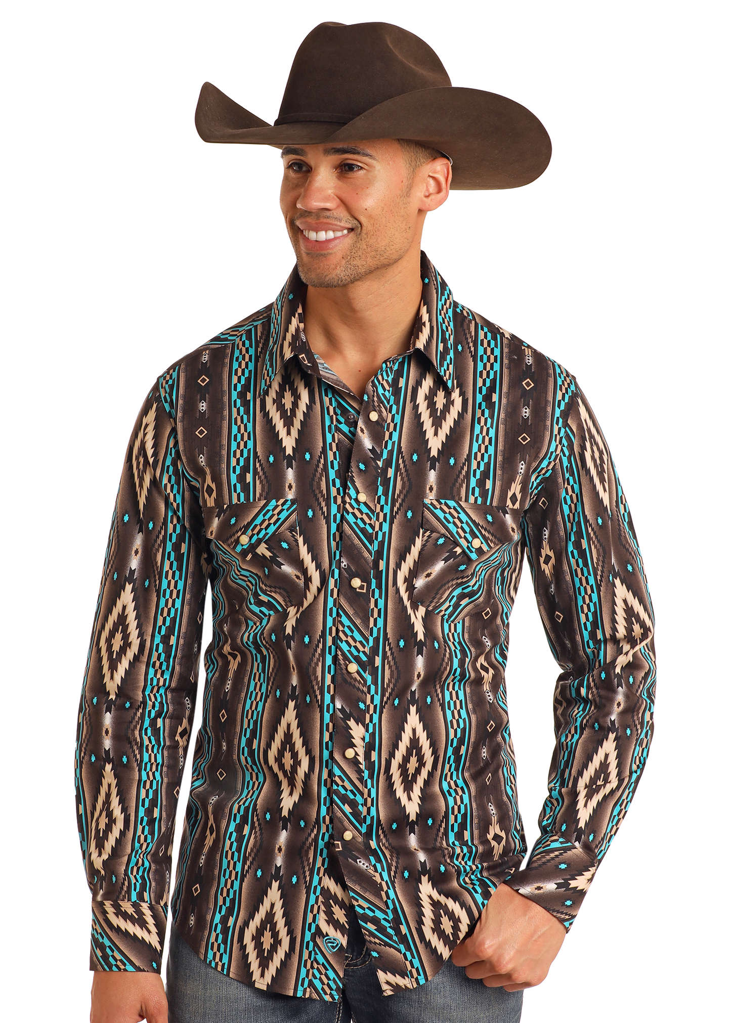 A smiling man in a Rock & Roll Denim Slim Fit Southwestern Striped Long Sleeve Snap Shirt, featuring turquoise, tan, and black geometric designs, stands casually with one hand in his pocket, wearing a cowboy hat and blue jeans.