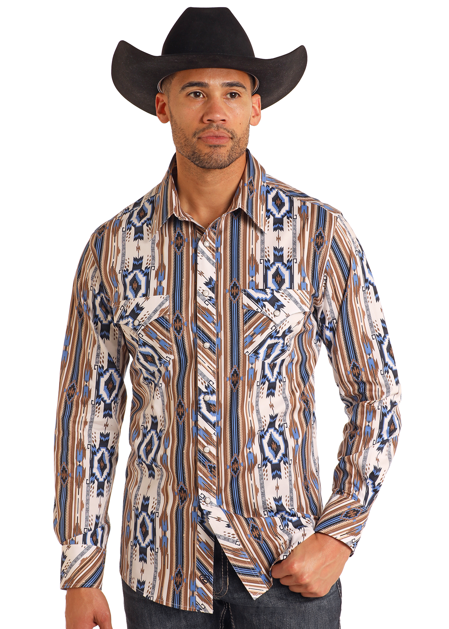 A man in a black cowboy hat, Rock & Roll Denim Slim Fit Tan Southwestern Striped Long Sleeve Snap Shirt, and dark jeans poses with one hand in his pocket against a plain background.
