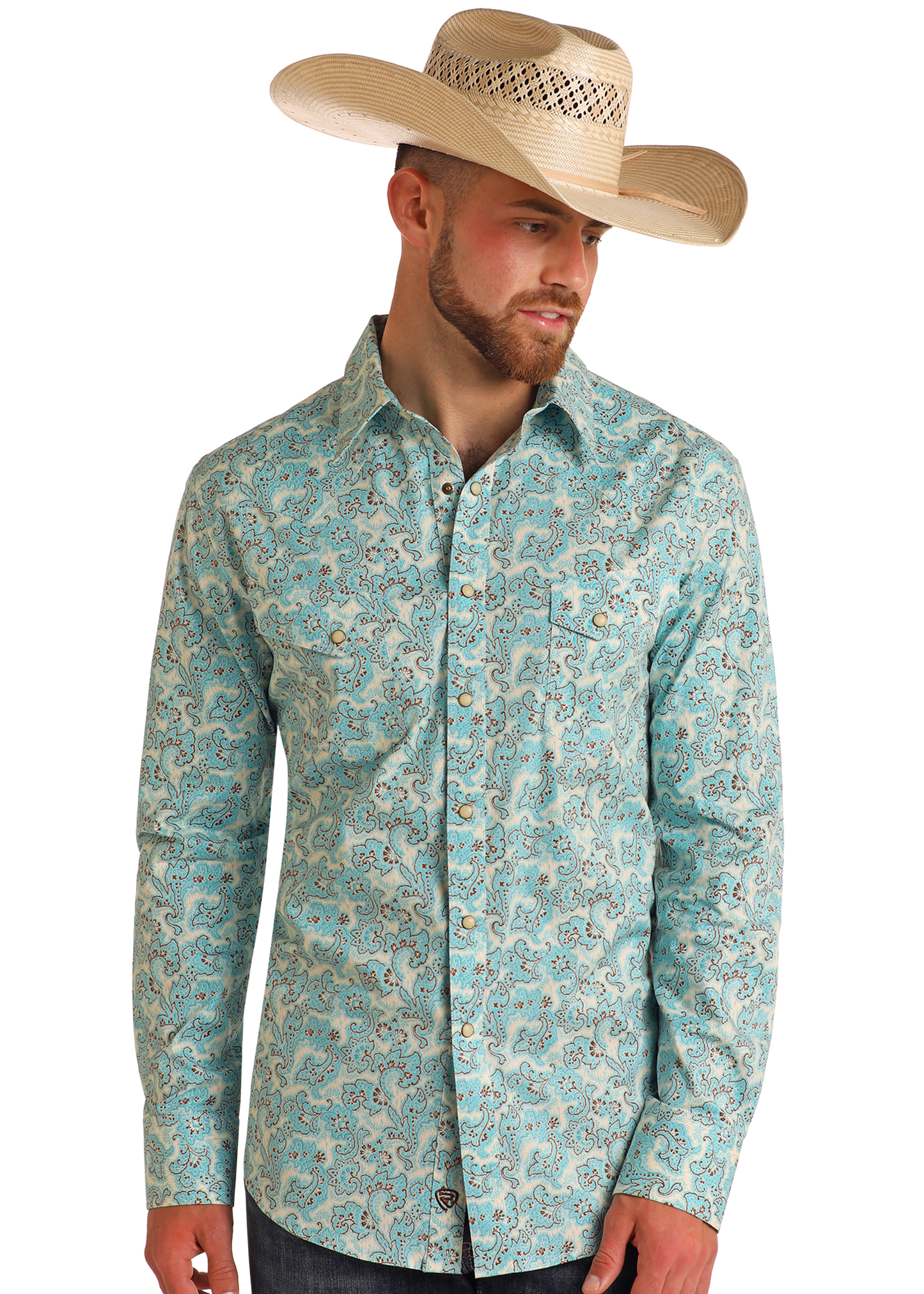 A man in a Rock & Roll Denim Slim Fit Turquoise Paisley Print Long Sleeve Snap Shirt, dark jeans, and a beige cowboy hat stands against a white background, gazing slightly left.