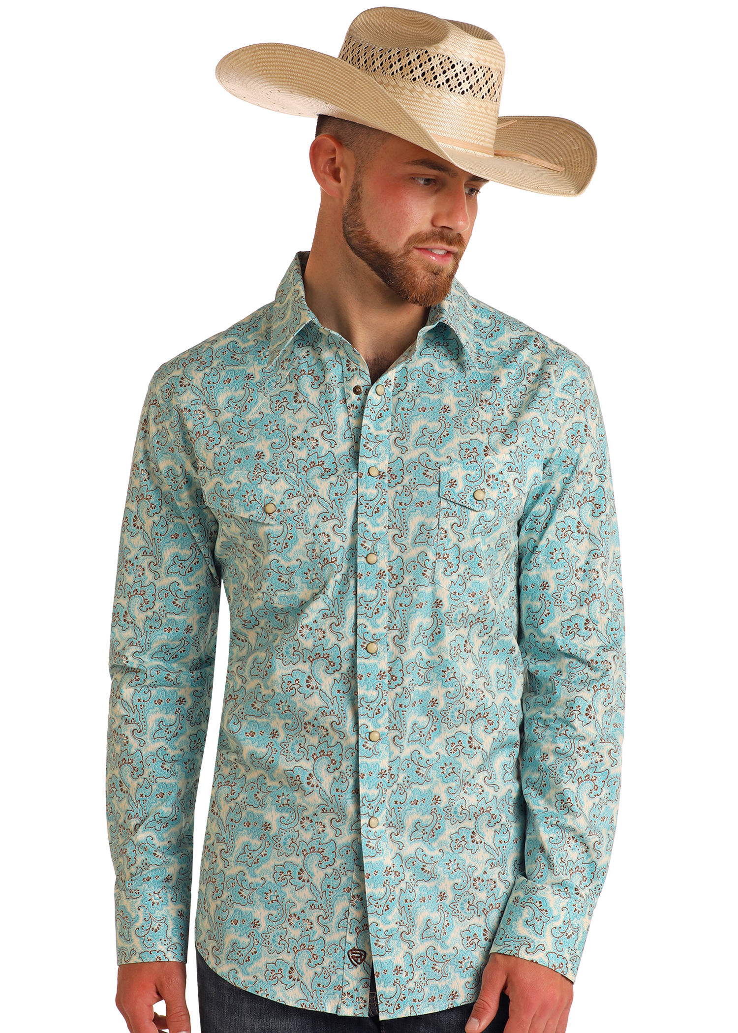 A man in a Rock & Roll Denim Slim Fit Turquoise Paisley Print Long Sleeve Snap Shirt, dark jeans, and a beige cowboy hat stands against a white background, gazing slightly left.