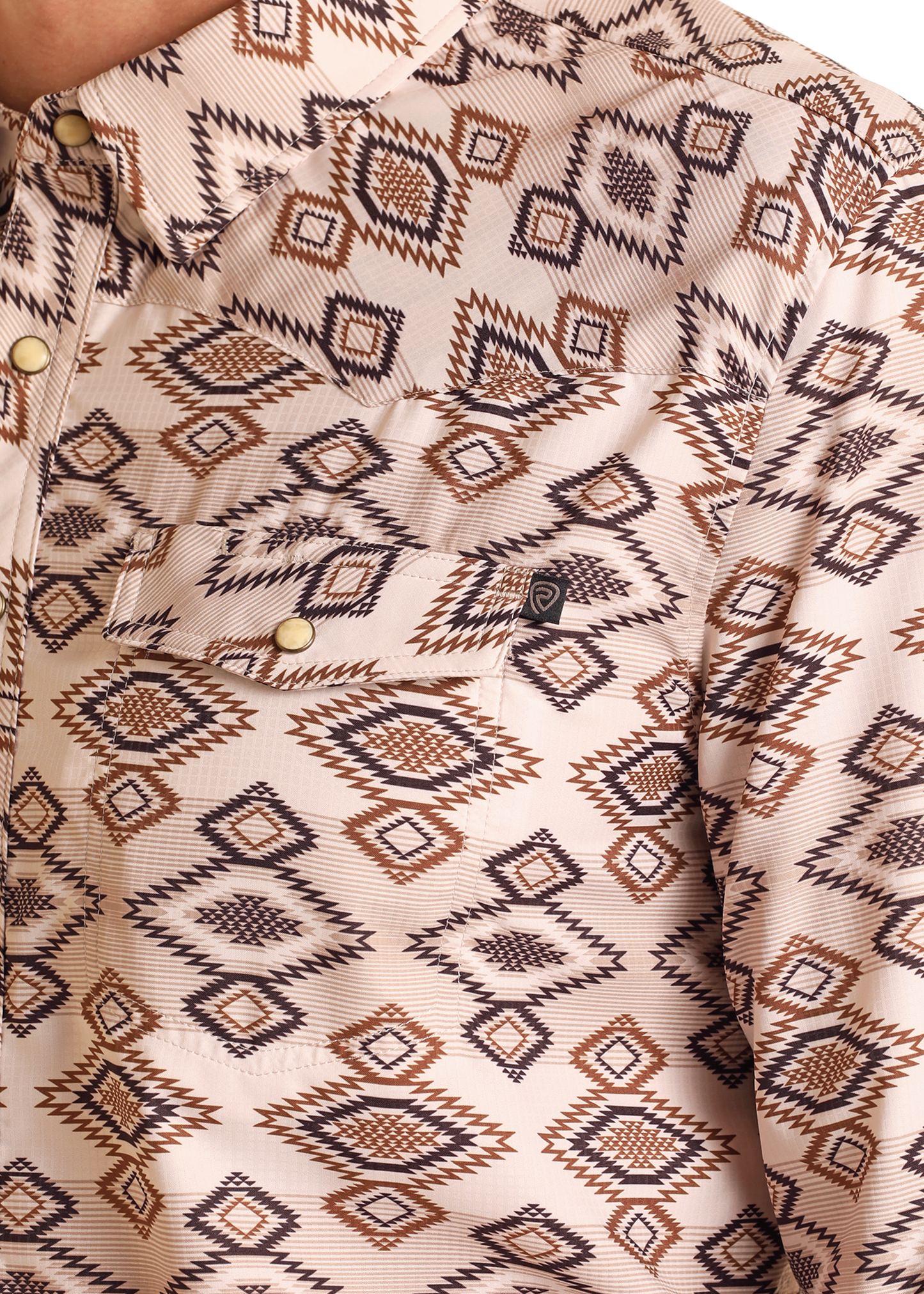 Close-up of the TEK Western Tan Aztec Diamond Long Sleeve Shirt by Rock & Roll Denim, featuring a beige geometric Southwestern-inspired pattern, pearl snap buttons, UPF 50 protection, and an embroidered logo on the chest pocket.