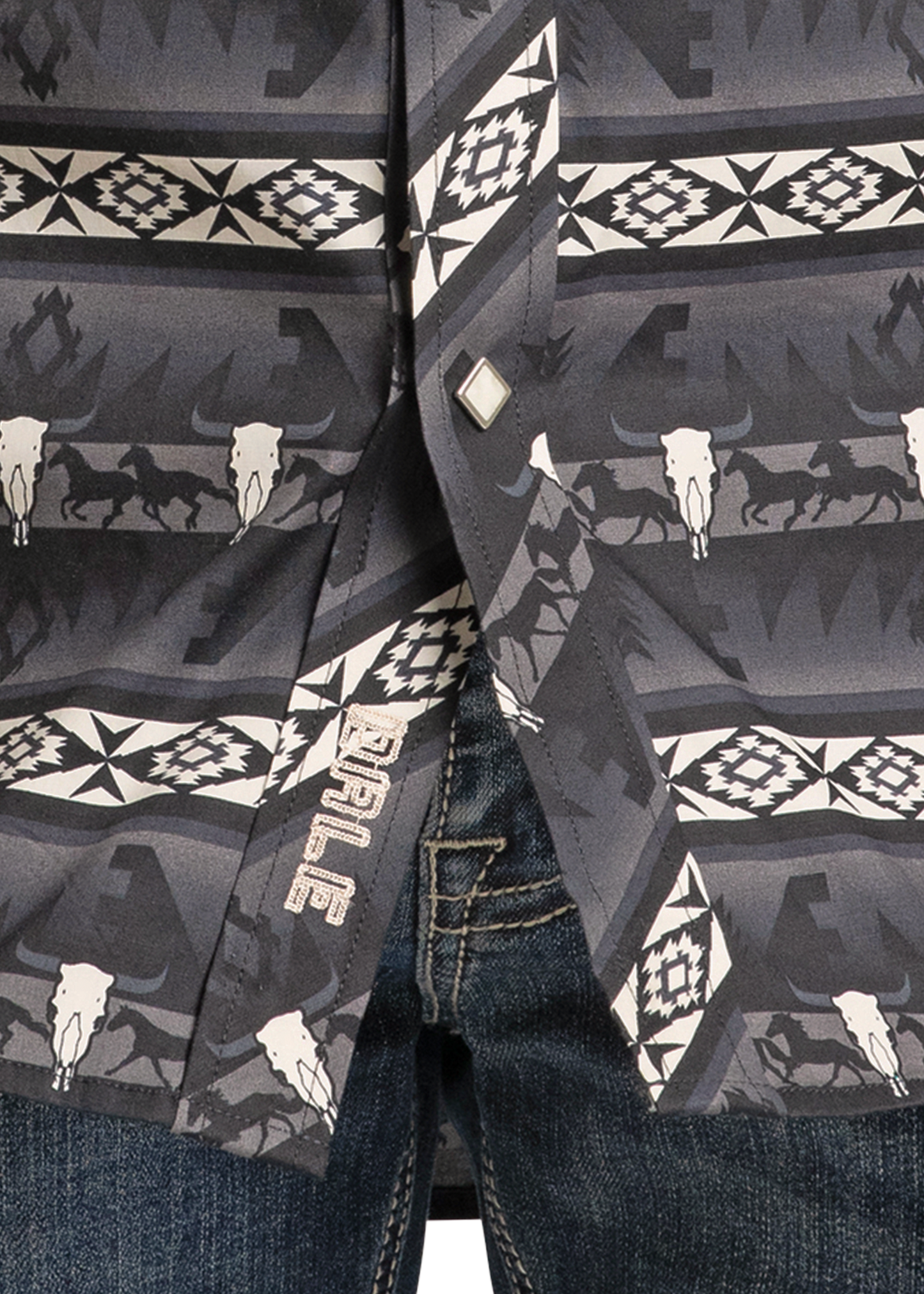 Close-up of the Dale Brisby Black Aztec Long Sleeve Snap Shirt by Rock & Roll Denim, featuring geometric and animal skull designs in black, white, and gray, worn over blue denim jeans. ROPER embroidered near the hem.
