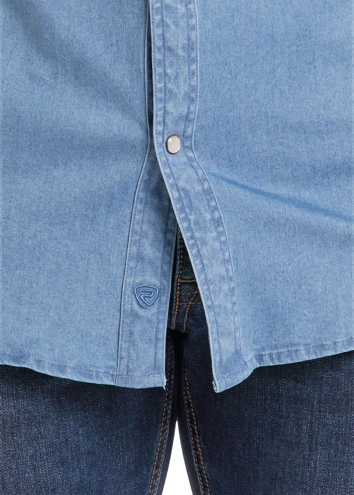 Close-up of a light blue denim button-up shirt worn over dark blue jeans, showing the button closure and fabric texture.