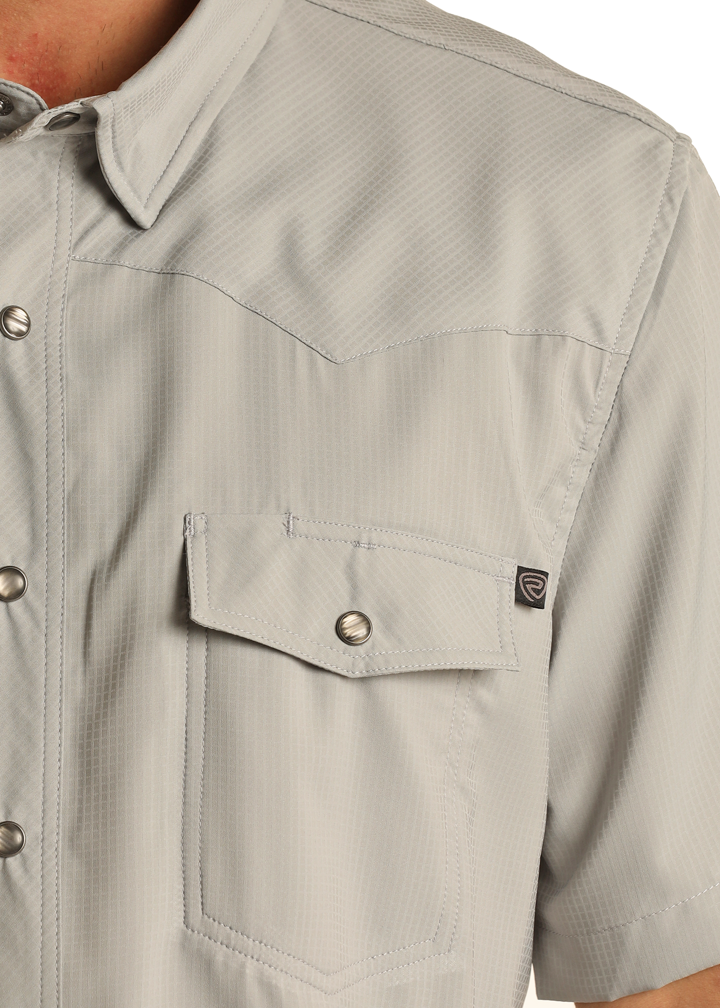 Close-up of the TEK Western Grey Short Sleeve Shirt by Rock & Roll Denim, featuring silver snap buttons, a flap chest pocket with a small black tag, subtle textured pattern, and UPF 50 sun protection.