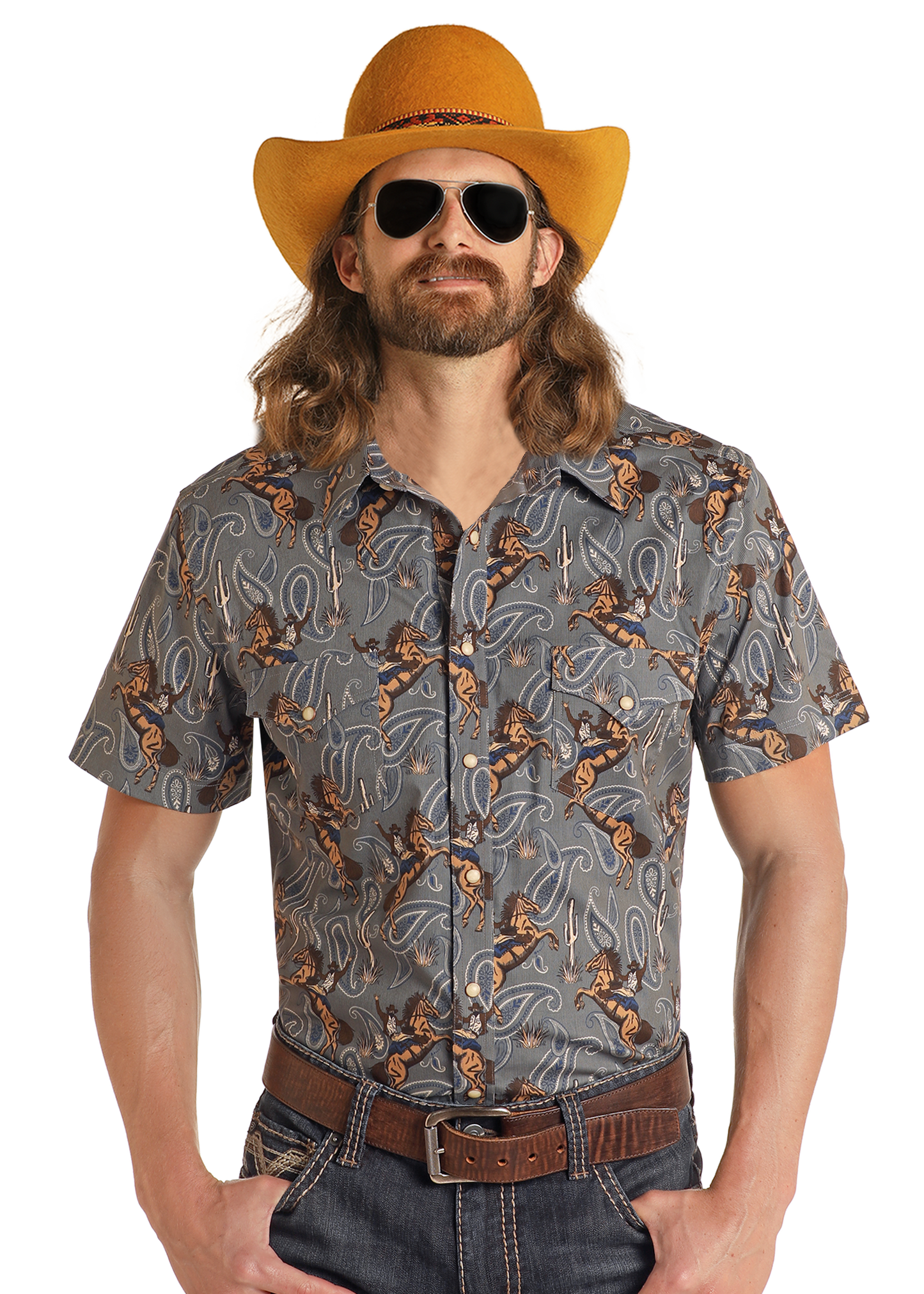 A man with long hair and a beard wears a yellow cowboy hat, sunglasses, jeans, a brown belt, and the Rock & Roll Denim Dale Brisby Slim Fit Cowboy Print Short Sleeve Snap Shirt, standing against a plain white background.