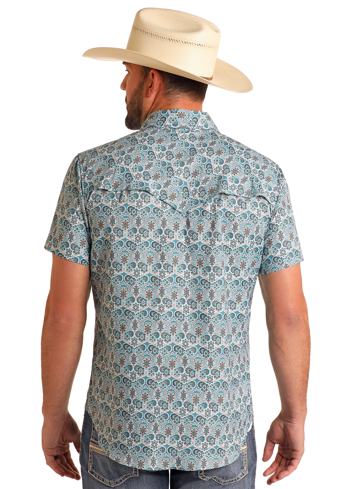 A man wearing a cream cowboy hat, blue jeans, and a Rock & Roll Denim TEK Western Geo Floral Print Short Sleeve Shirt stands with his back to the camera against a plain white background.