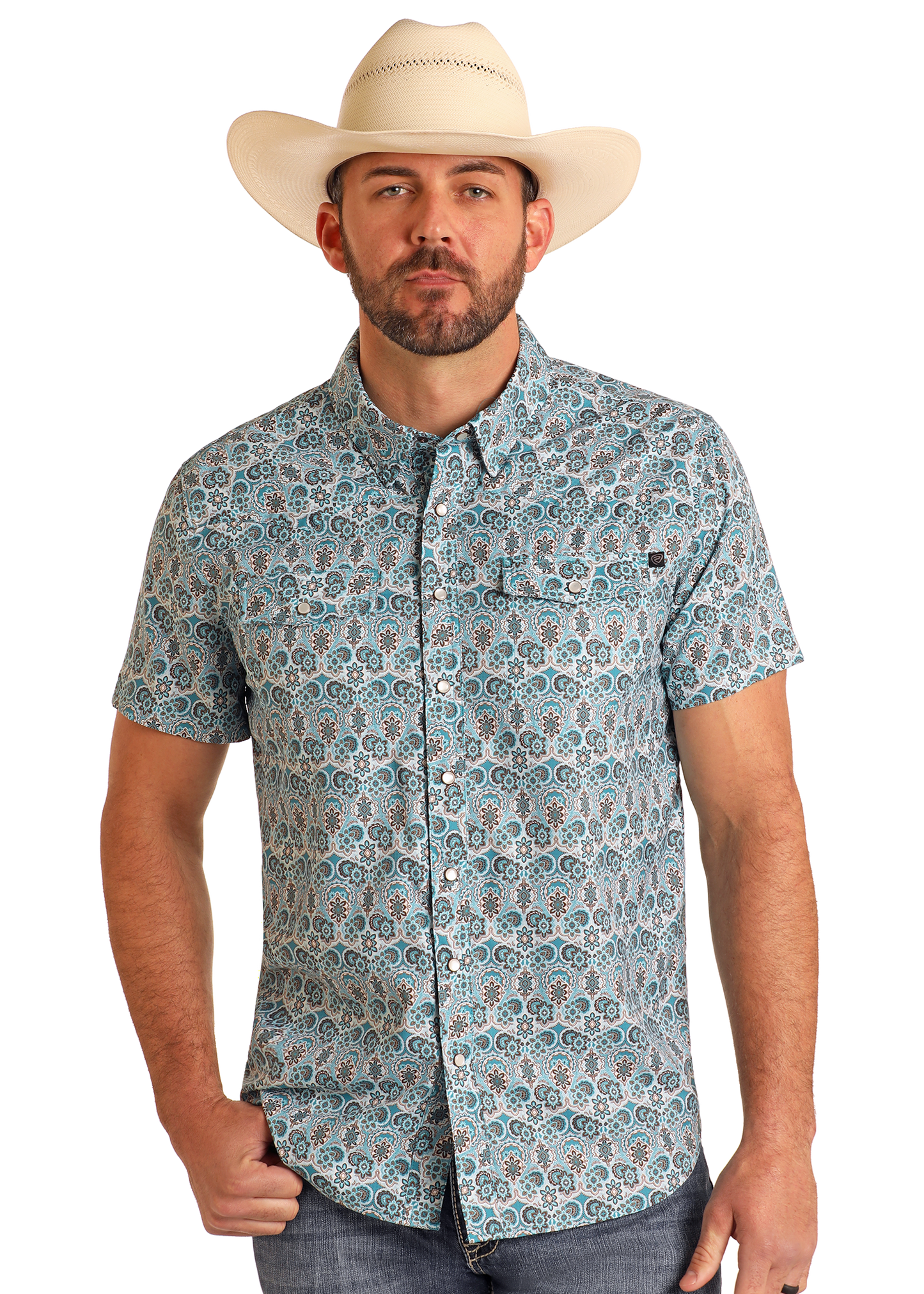A man wearing a white cowboy hat and the Rock & Roll Denim TEK Western Geo Floral Print Short Sleeve Shirt with a blue and white geometric pattern stands facing forward, one hand in his pocket, against a plain background.