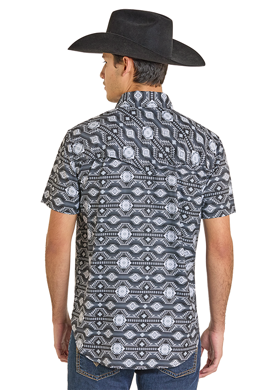 A man wearing the Rock & Roll Denim TEK Western Black & Grey Aztec Short Sleeve Shirt with UPF 50 faces away, showing the back of his outfit. He pairs the shirt with blue jeans and a black cowboy hat.