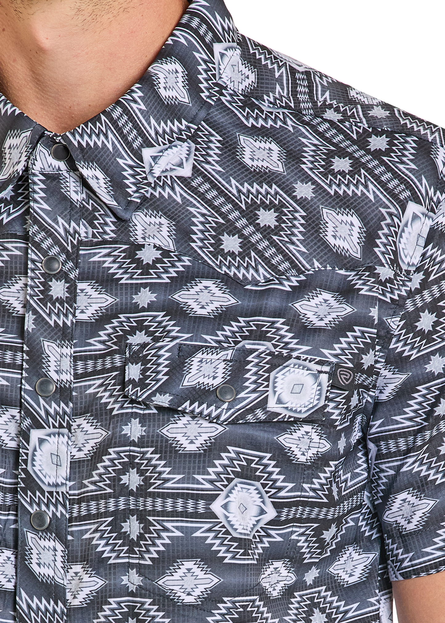 A close-up of a person wearing the Rock & Roll Denim TEK Western Black & Grey Aztec Short Sleeve Shirt, featuring two chest pockets, metal snap buttons, and moisture-wicking comfort.