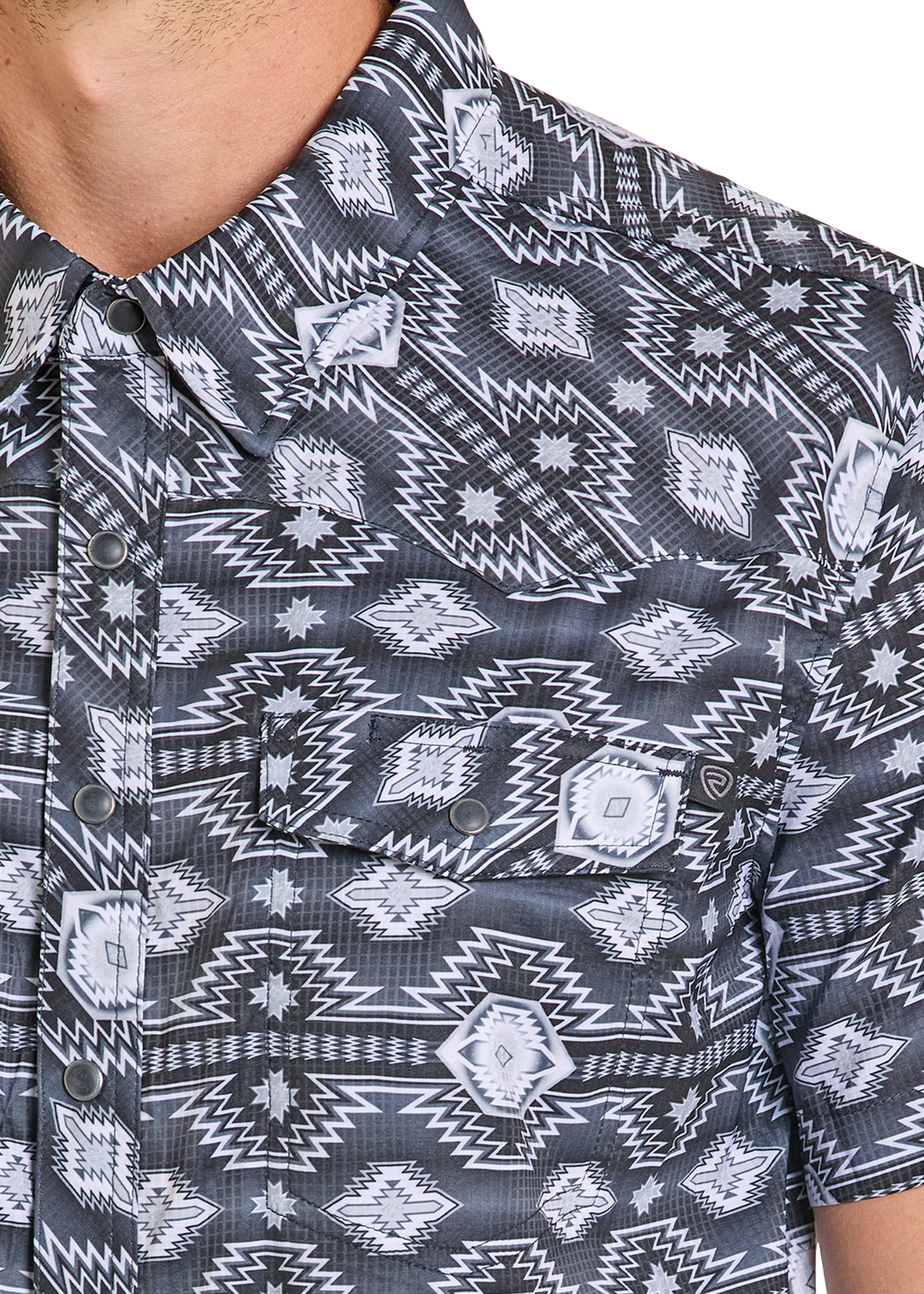 A close-up of a person wearing the Rock & Roll Denim TEK Western Black & Grey Aztec Short Sleeve Shirt, featuring two chest pockets, metal snap buttons, and moisture-wicking comfort.