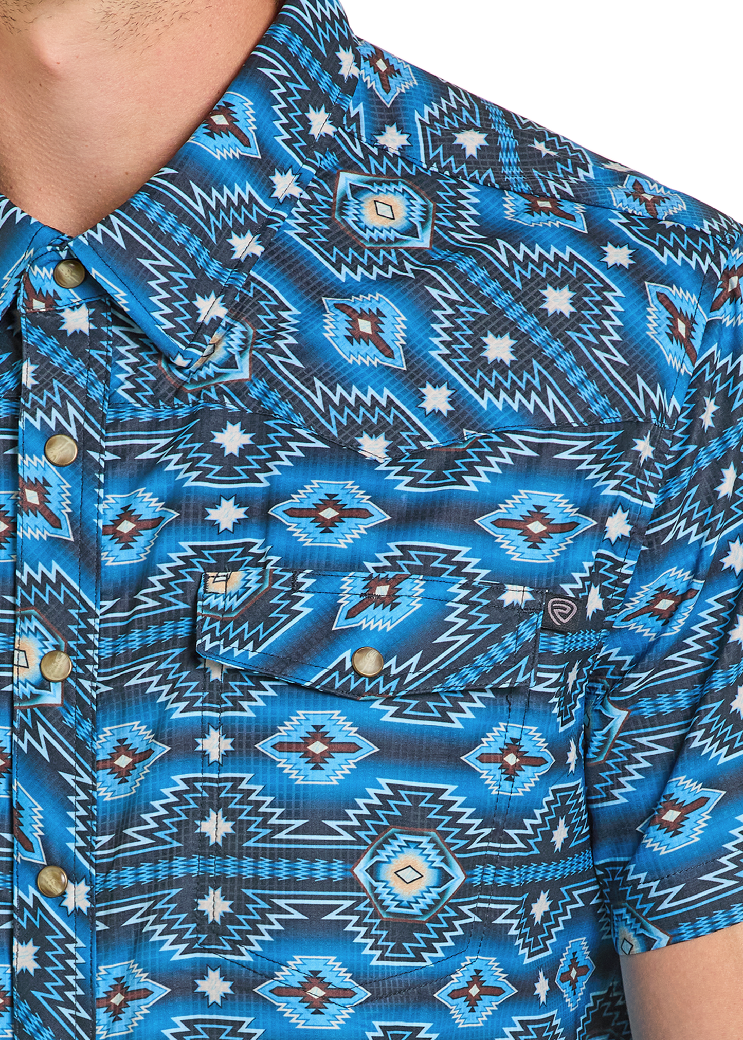 Close-up of a person wearing the Rock & Roll Denim TEK Western Blue on Blue Aztec Short Sleeve Shirt, featuring an intricate geometric and Southwestern-inspired pattern; part of the neck, shoulder, and chest are visible.