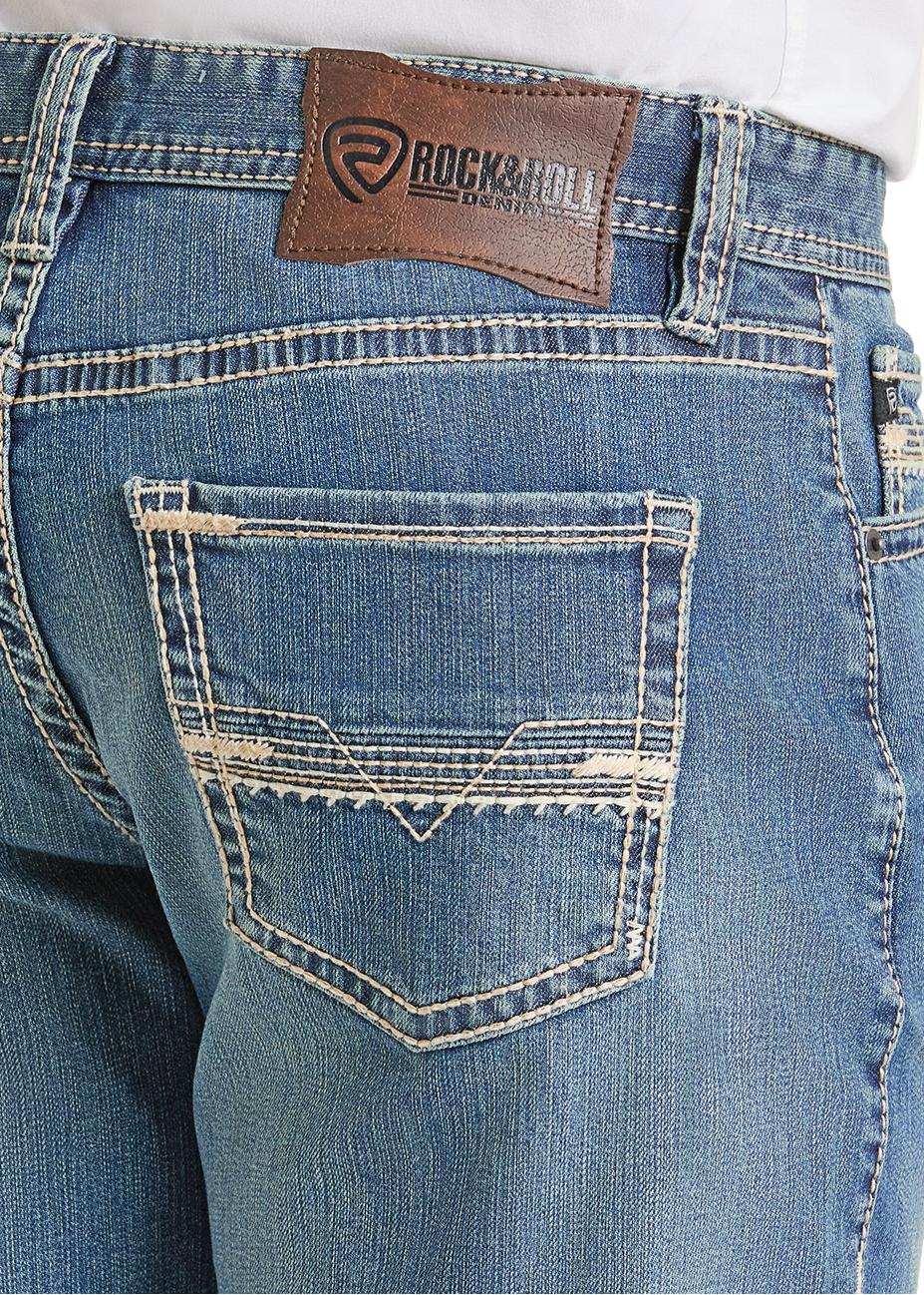 Close-up of the back of a person wearing light blue Relaxed Fit Classic Ladder V Stackable Bootcut Jeans by Rock & Roll Denim, featuring a brown leather brand label and distressed stitching on the back pocket.