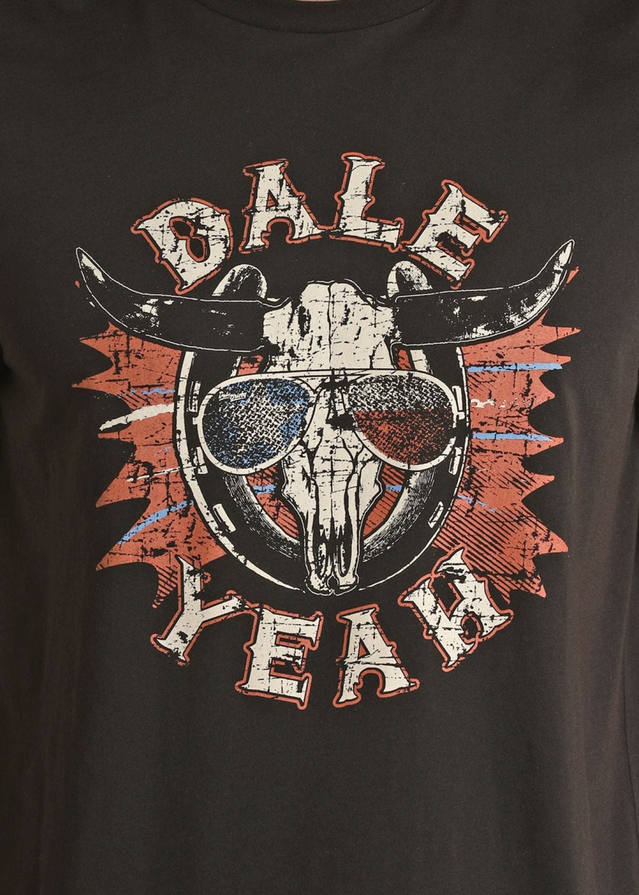 The Dale Brisby American Dale Yeah Graphic Tee by Rock & Roll Denim showcases a steer skull in Texas flag sunglasses, red and blue paint splatters, and “DALE YEAH” text—a bold American style inspired by Dale Brisby.
