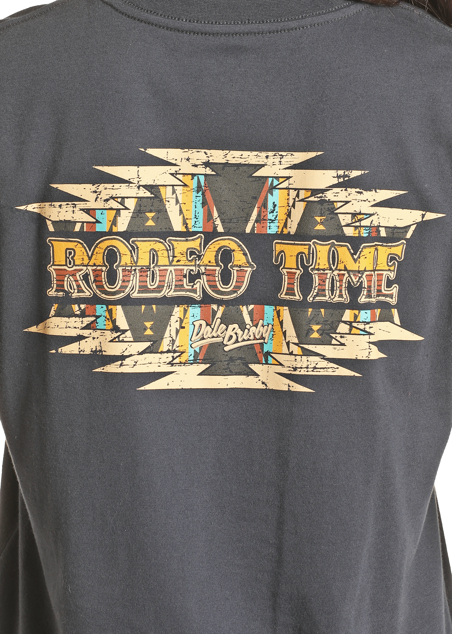 The Dale Brisby Rodeo Time Tee by Rock & Roll Denim is a black Western graphic shirt with bold geometric patterns and distressed yellow-orange “RODEO TIME” lettering, plus Dale Brisby’s script below a Southwestern-inspired design.