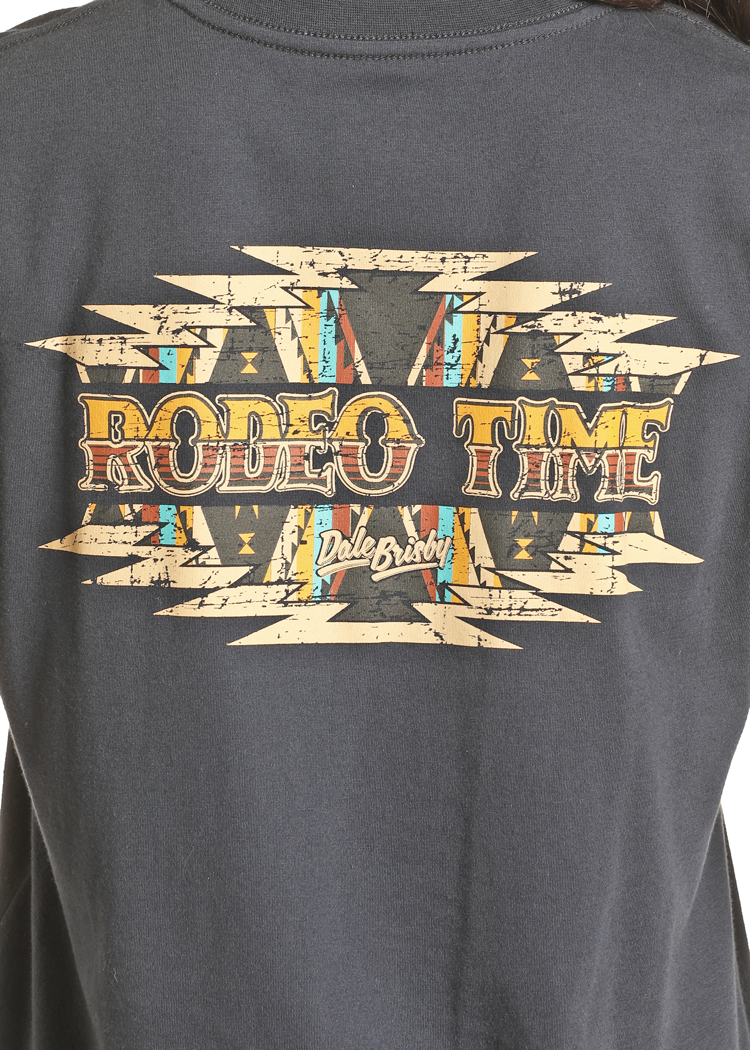 The Dale Brisby Rodeo Time Tee by Rock & Roll Denim is a black Western graphic shirt with bold geometric patterns and distressed yellow-orange “RODEO TIME” lettering, plus Dale Brisby’s script below a Southwestern-inspired design.