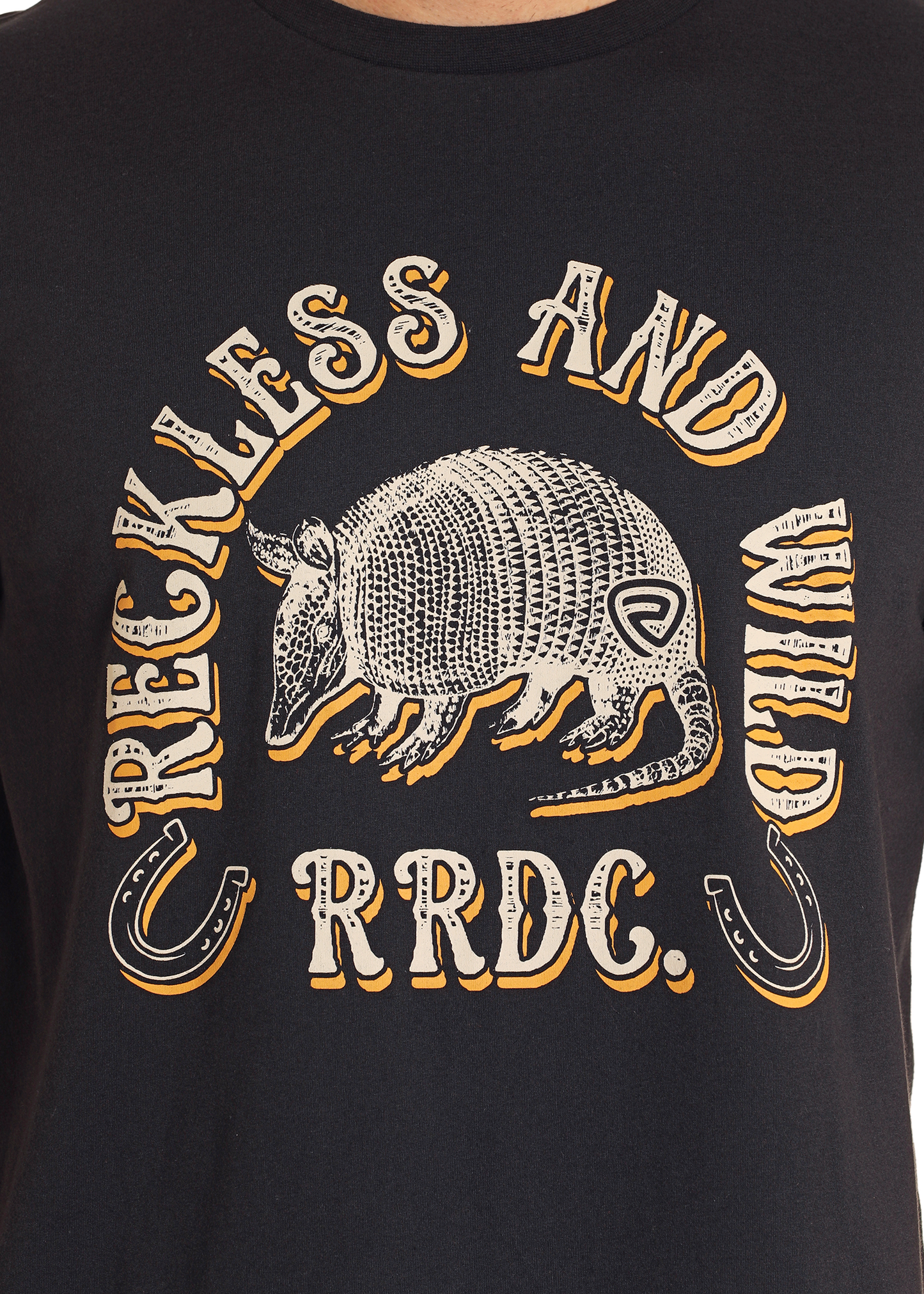 The Rock & Roll Denim Armadillo Graphic Tee showcases an illustrated armadillo, “RECKLESS AND WILD” and “RRDC” text, plus horseshoe graphics—delivering everyday comfort and standout Western style.
