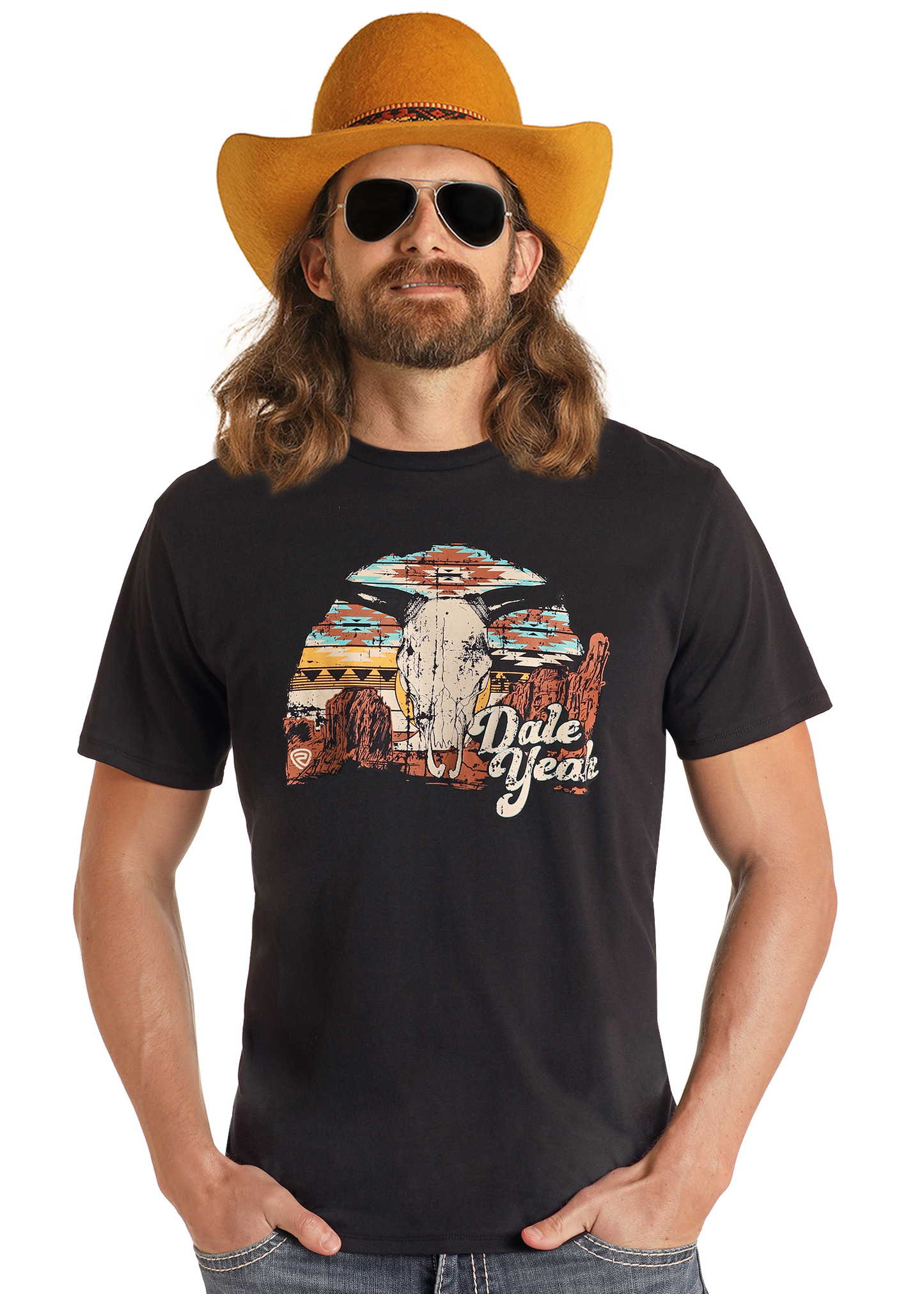 A man with long hair and a beard wears a yellow cowboy hat, black sunglasses, and the Rock & Roll Denim Dale Brisby Black Dale Yeah Graphic Tee (size S), featuring a colorful desert scene. He smiles slightly with his hands in his pockets.