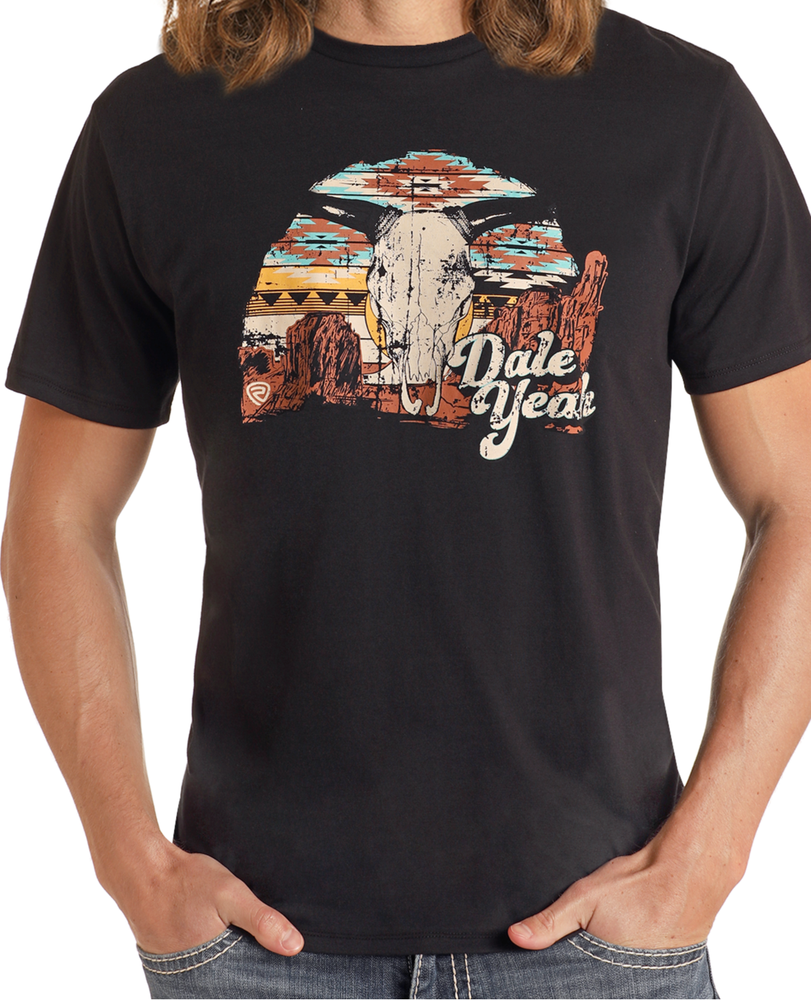 Someone with long hair wears the Rock & Roll Denim Dale Brisby Black Dale Yeah Graphic Tee—a comfy cotton-polyester shirt featuring a bold “Dale Yeah” design with a bull skull, sunset, desert scene, and red rock formations.