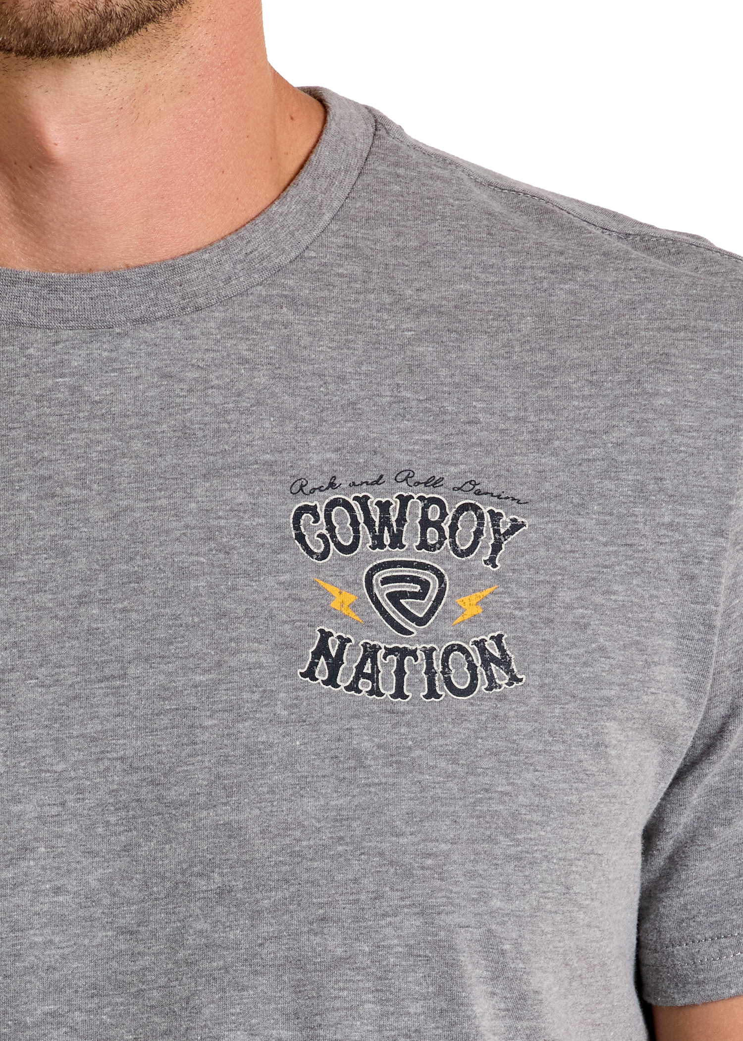 Close-up of a person wearing the Cowboy Nation Graphic Tee by Rock & Roll Denim, a comfy heather gray shirt featuring decorative script, yellow lightning bolts, and a circular emblem—ideal for everyday style.