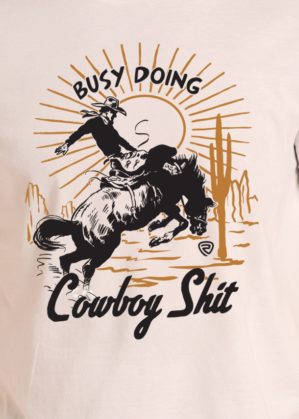 A man wearing a black cowboy hat and a light beige graphic t-shirt with a western design, standing against a plain white background.