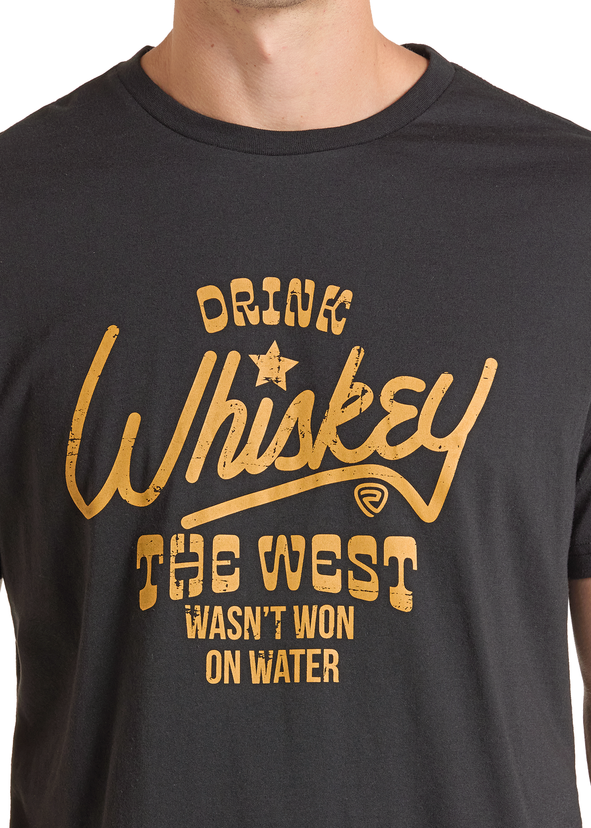 A close-up of a person wearing a dark charcoal gray t-shirt with a distressed gold graphic that reads 'DRINK Whiskey THE WEST WASN'T WON ON WATER'.