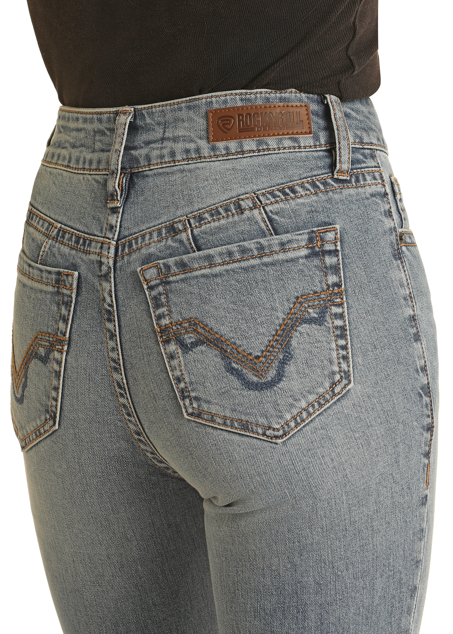 Close-up of a person in Rock & Roll Denim's Mid Rise Distressed Modest Bootcut Jeans featuring light blue denim, brown stitching, a leather brand patch, and decorative back pocket details, paired with a tucked-in black top.