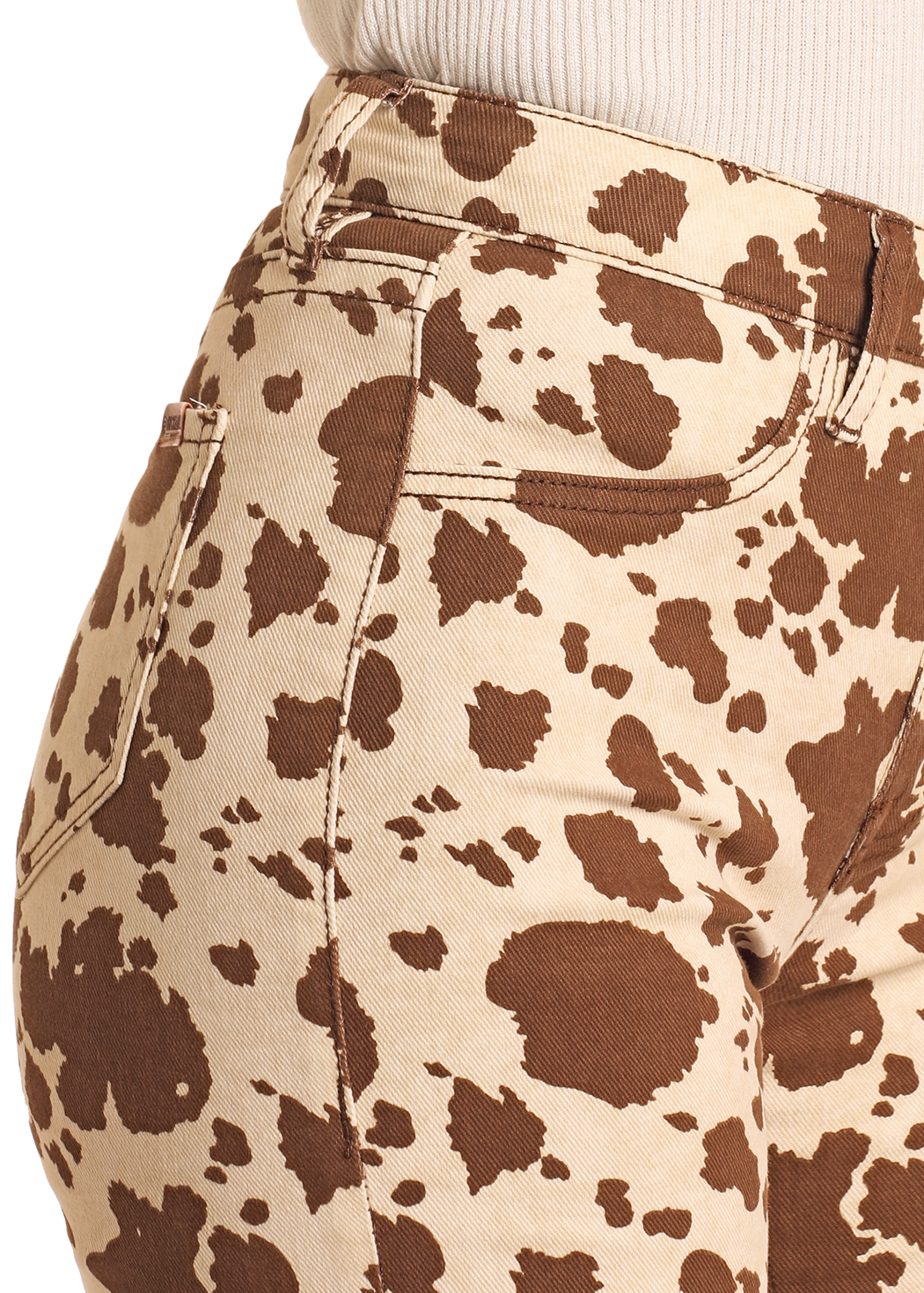 A person wearing Rock & Roll Denim Cowhide Print Modest Bootcut Jeans, featuring a brown and beige cow print pattern, paired with a light beige ribbed top; shown from waist to mid-thigh in a side profile.
