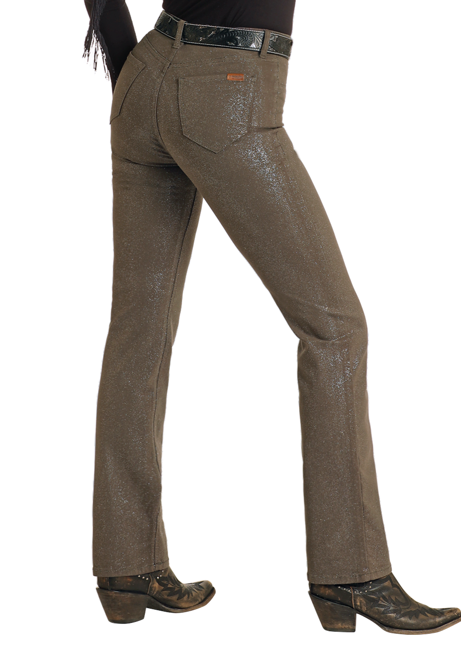 A person wears Rock & Roll Denim Glitter Extra Stretch Modest Bootcut Jeans, a black belt, and black cowboy boots, posing with one leg slightly bent against a white background.