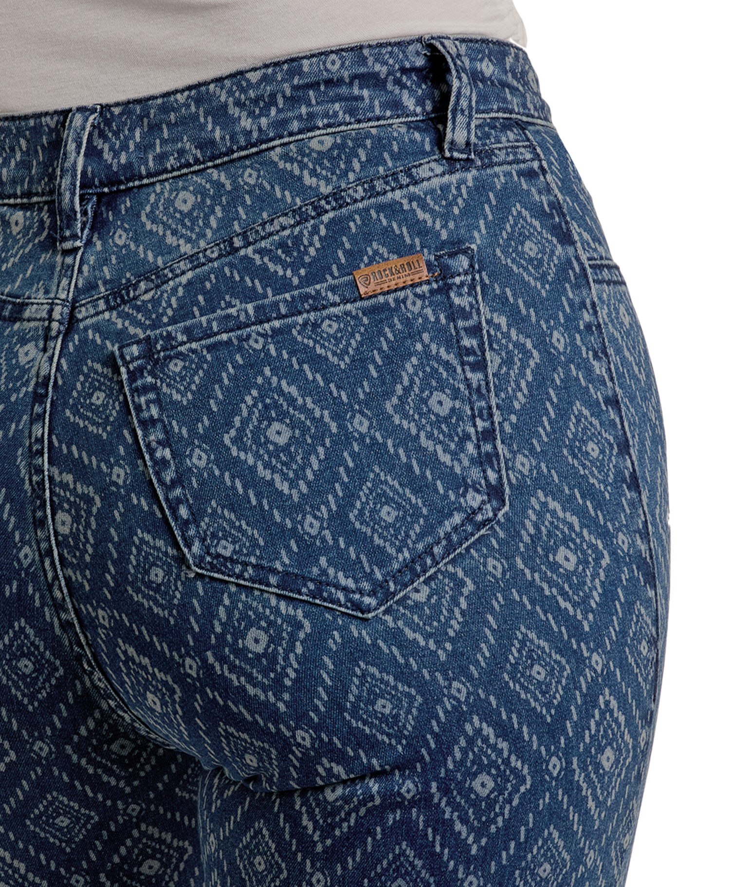 Close-up of a person wearing Rock & Roll Denim High Rise Diamond Bootcut Jeans with a white geometric diamond pattern, highlighting the back pocket and brown label above the waistband.