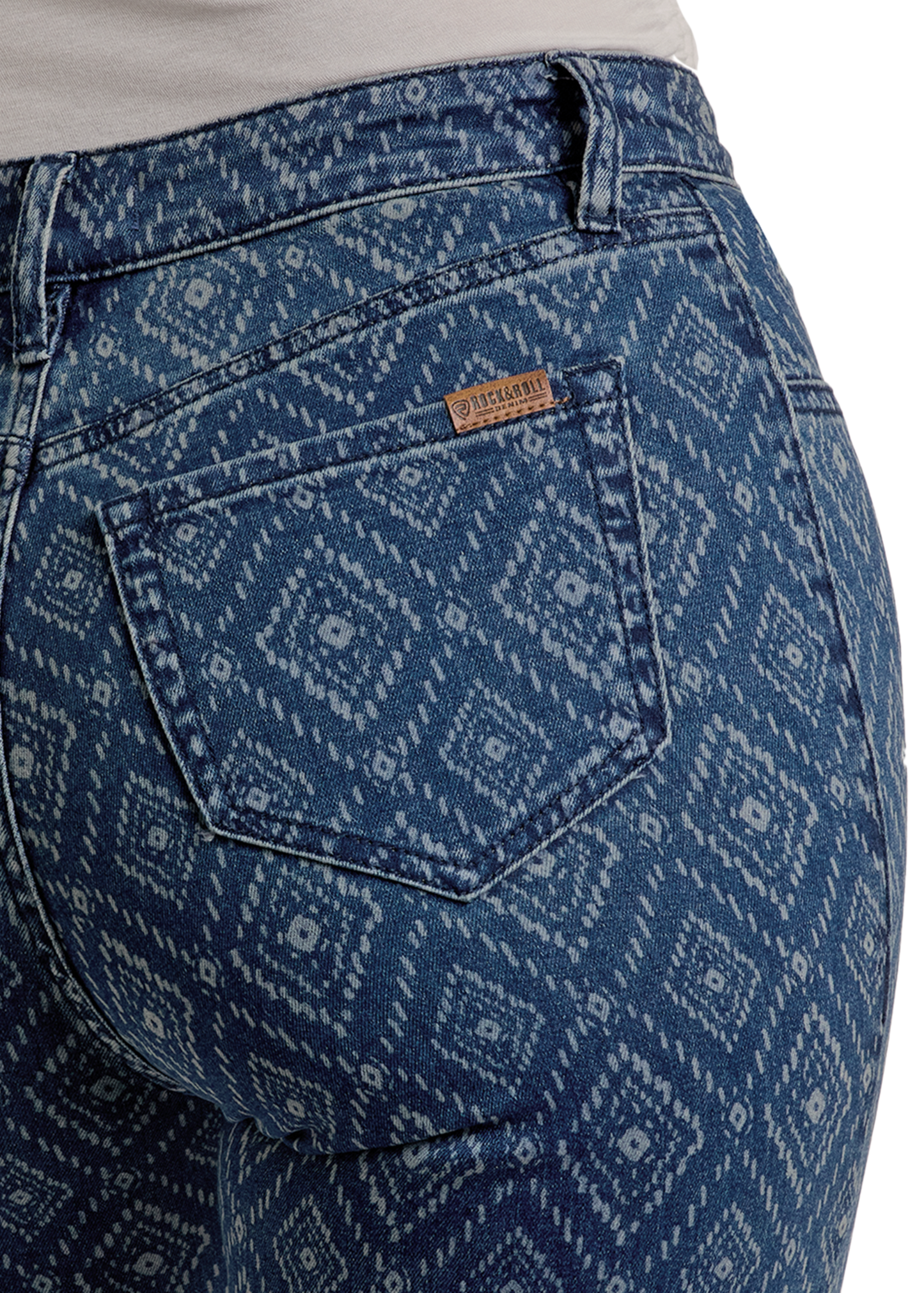 Close-up of a person wearing Rock & Roll Denim High Rise Diamond Bootcut Jeans with a white geometric diamond pattern, highlighting the back pocket and brown label above the waistband.