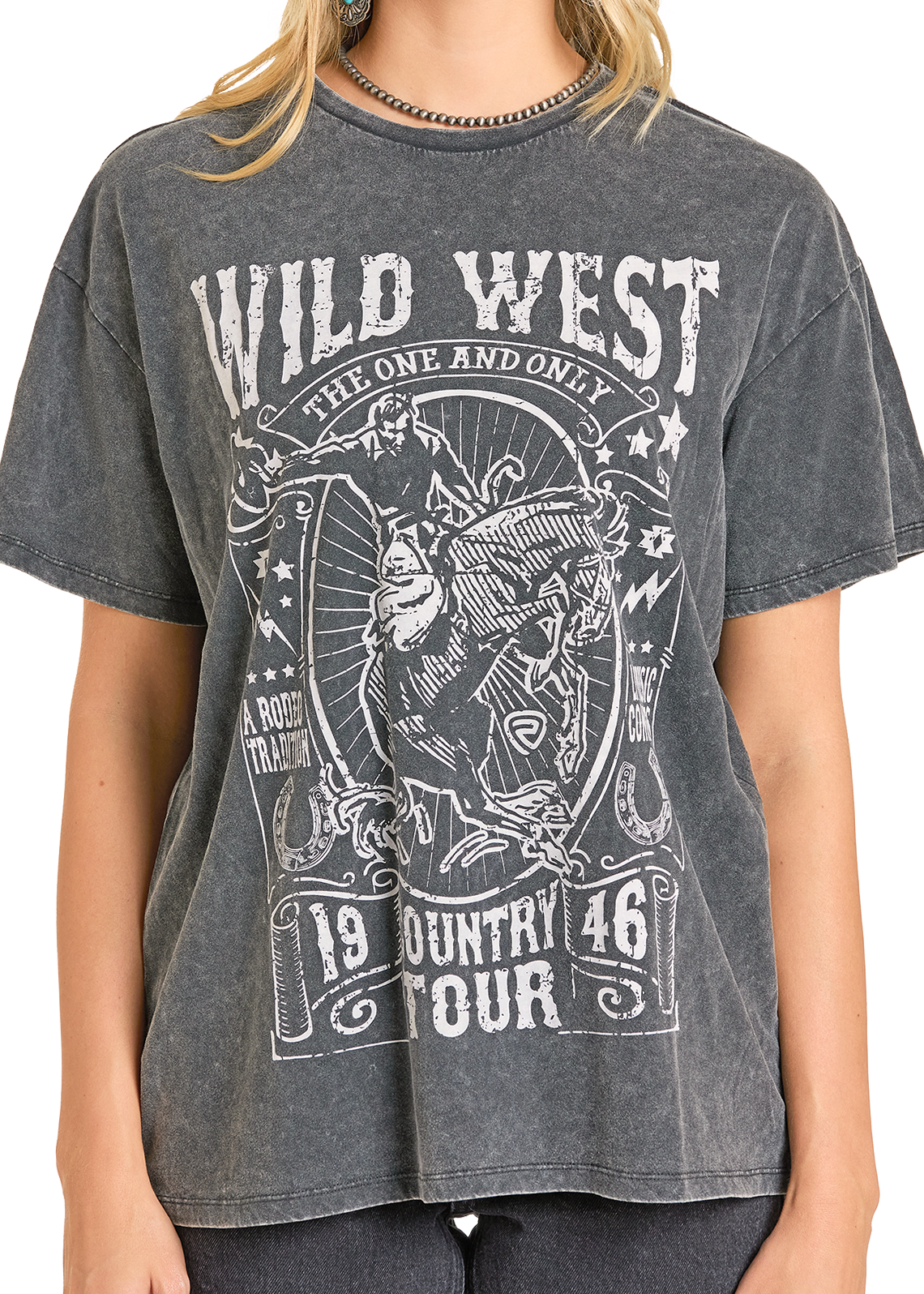 A person wears a faded black Wild West Oversized Tee by Rock & Roll Denim, featuring a cowboy riding a bucking horse and vintage-style western lettering; the wearer's head is partially out of frame.