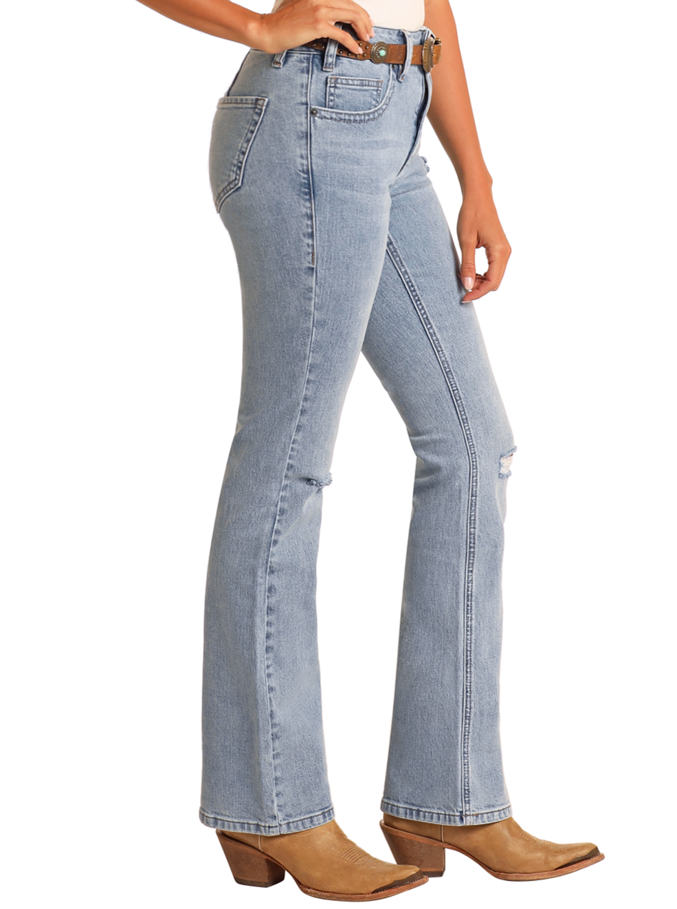 A person wears Rock & Roll Denim High Rise Light Wash Bootcut Jeans with front distressing, styled with a belt and brown heeled boots, shown from the side against a plain background.
