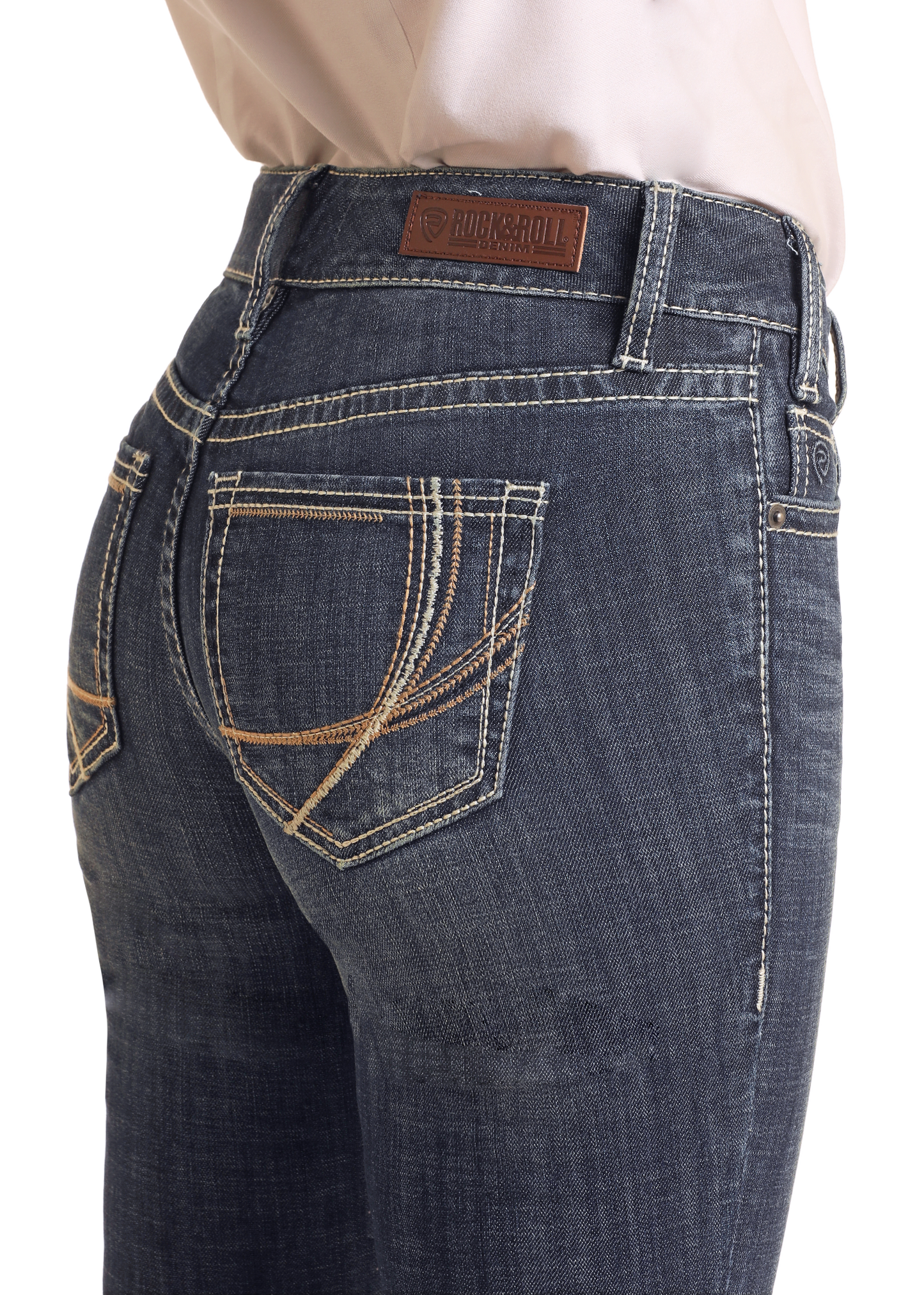 A close-up of someone wearing Rock & Roll Denim Mid Rise Curved Stitch Bootcut Riding Jeans, featuring decorative back pocket stitching and a brown leather brand patch for a stylish, comfortable look.