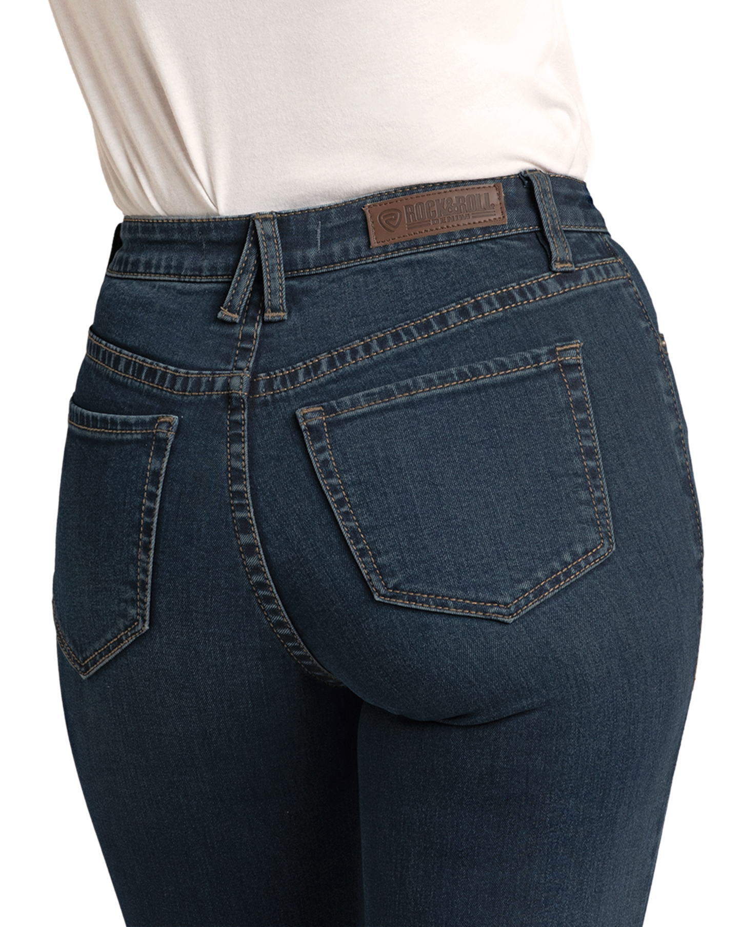 A person wearing Rock & Roll Denim High Rise Stretch Dark Wash Trousers and a white shirt is shown from the back waist down. The trousers feature back pockets, a leather patch label, and visible stitching.