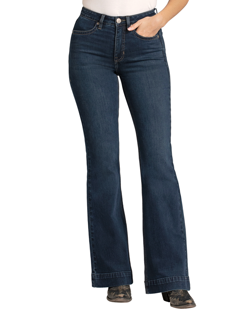 A person models Rock & Roll Denim's High Rise Stretch Dark Wash Trousers with a white top and black heeled boots, standing against a plain background, one hand in their pocket.