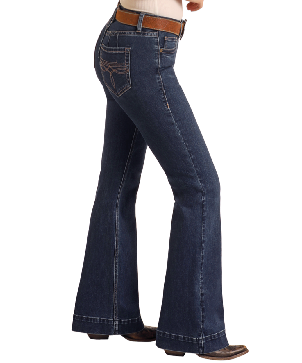 Person wearing Rock & Roll Denim Mid Rise Boot Stitch Trousers with a tan belt and brown shoes, standing sideways with hand in front pocket against a plain white background.