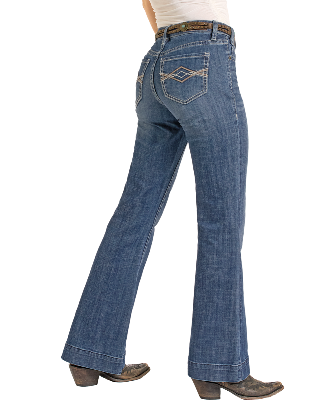 A person wears Rock & Roll Denim’s Mid Rise Pleather Embroidered Trousers with a brown belt, white shirt, and brown cowboy boots, standing with one leg forward against a white background.