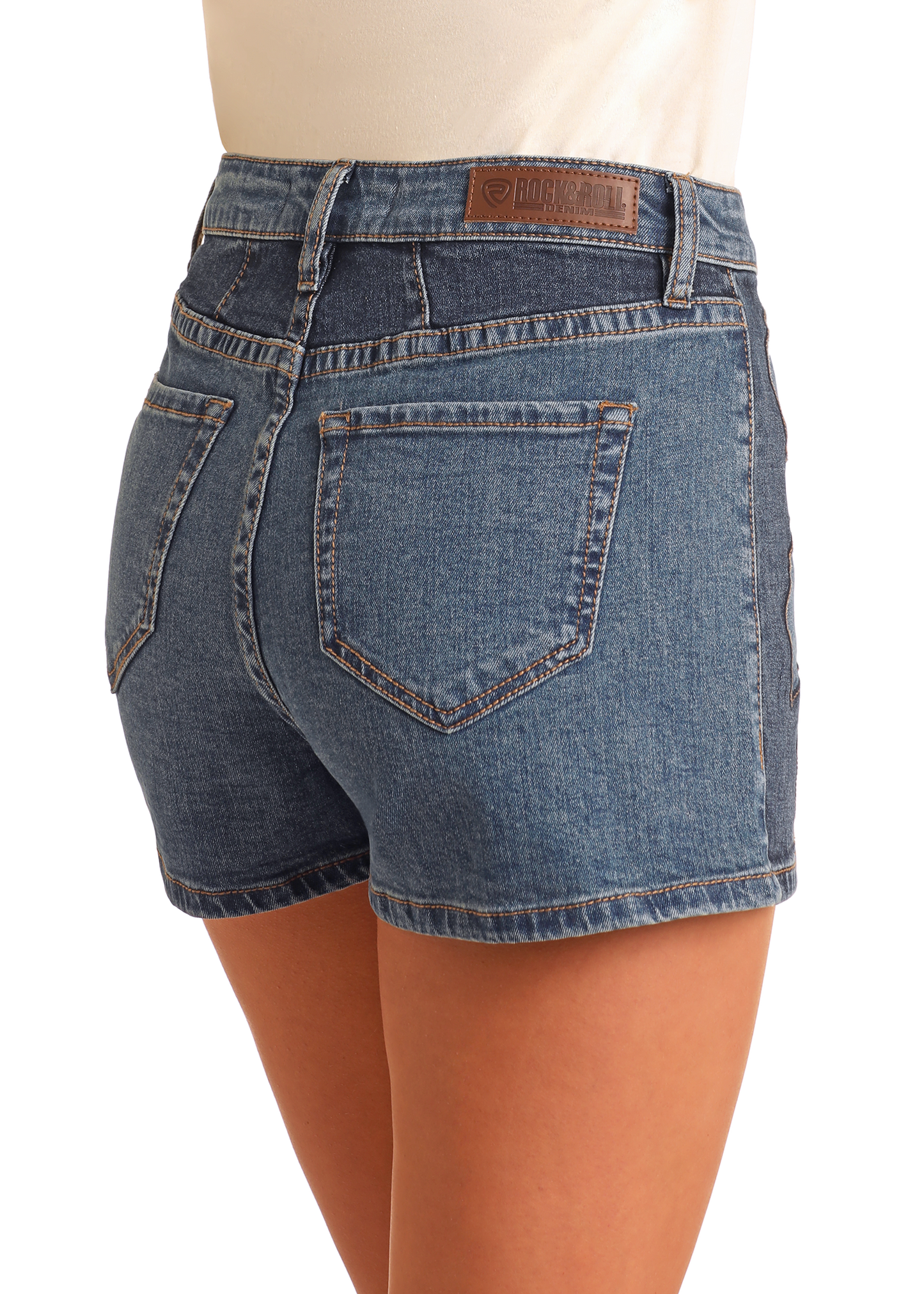 A person wearing Rock & Roll Denim Extra Stretch Western Applique Shorts with visible back pockets and a brown leather patch on the waistband, shown from behind against a plain background—versatile festival-ready style.