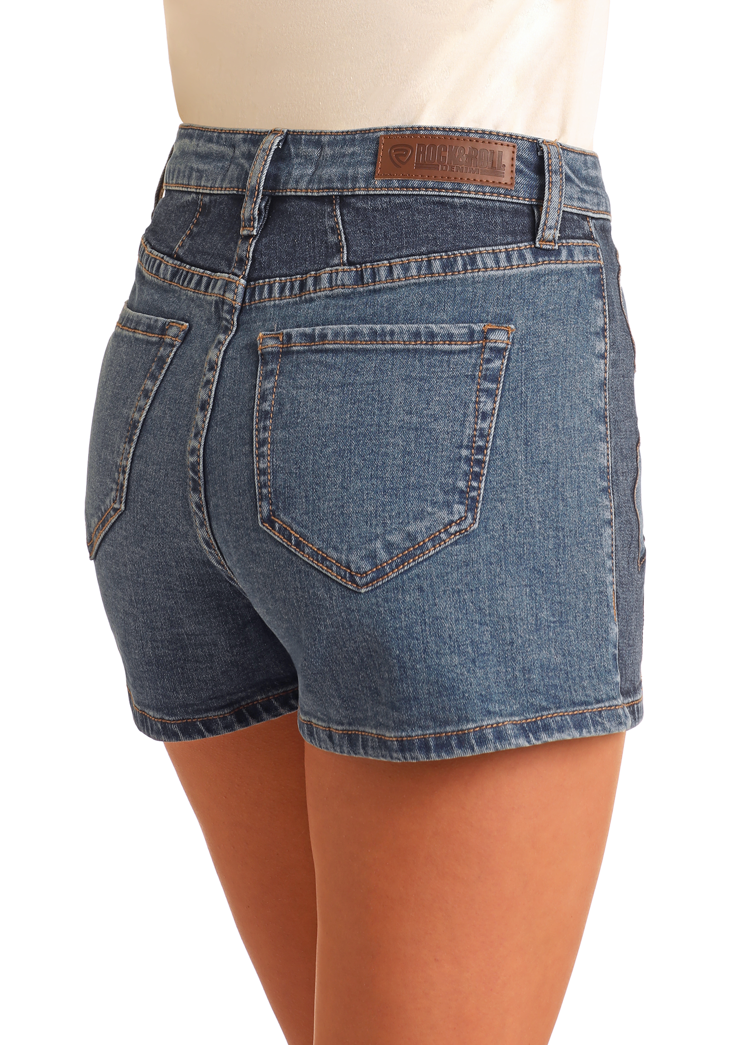 A person wearing Rock & Roll Denim Extra Stretch Western Applique Shorts with visible back pockets and a brown leather patch on the waistband, shown from behind against a plain background—versatile festival-ready style.