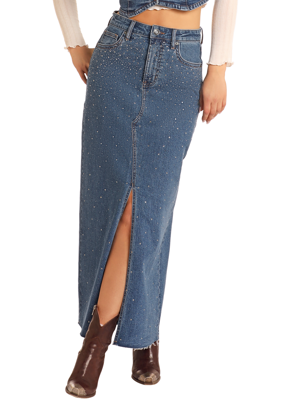 A woman wears the Rock & Roll Denim Studded Denim Maxi Skirt with rhinestone details, front slit, and frayed hem, paired with brown ankle boots and a cream long-sleeve top.