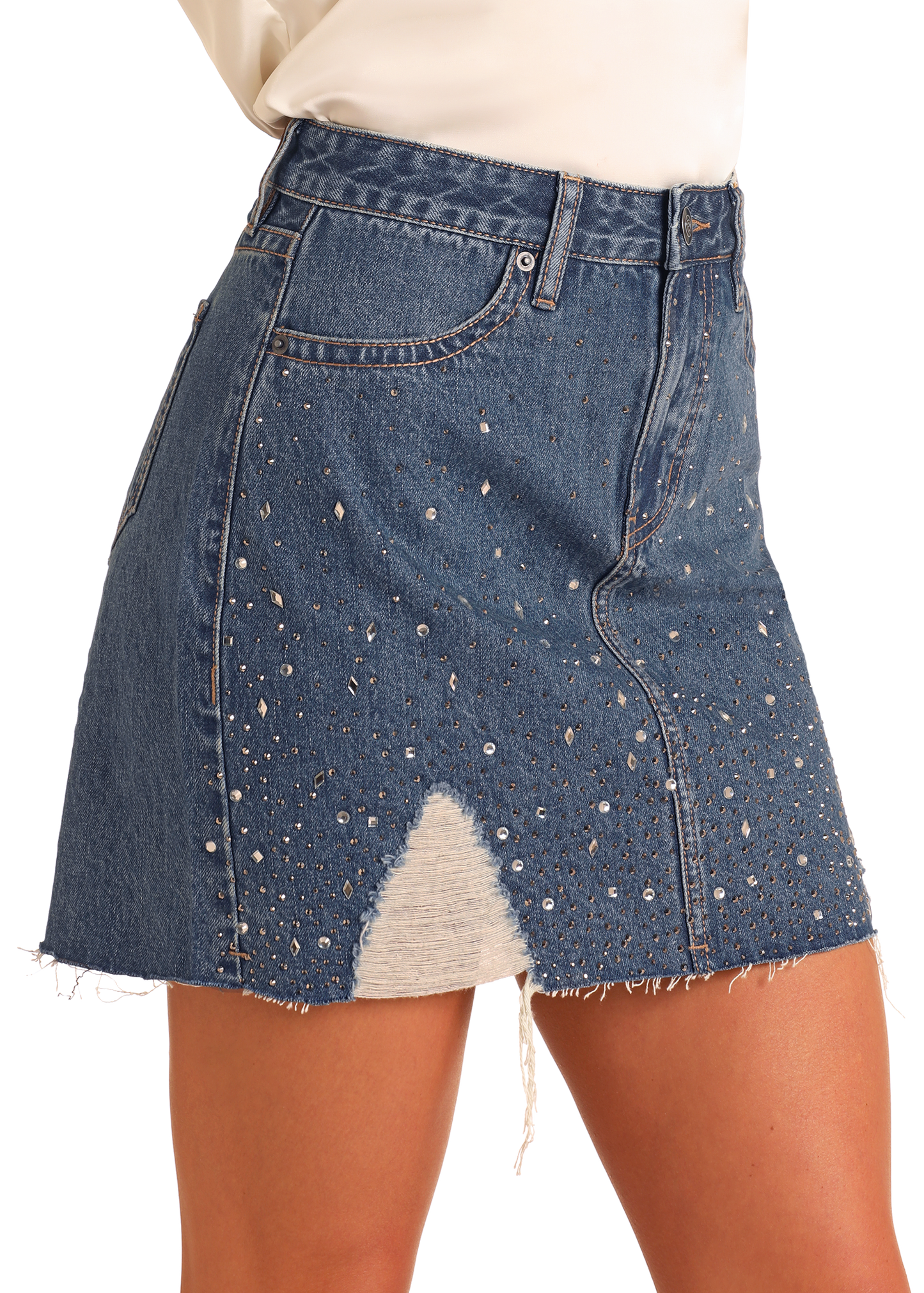 A woman wears the Rock & Roll Denim Distressed Studded Denim Mini Skirt, featuring a high-rise fit, frayed hem, silver studs, and a triangular distressed patch on the front.
