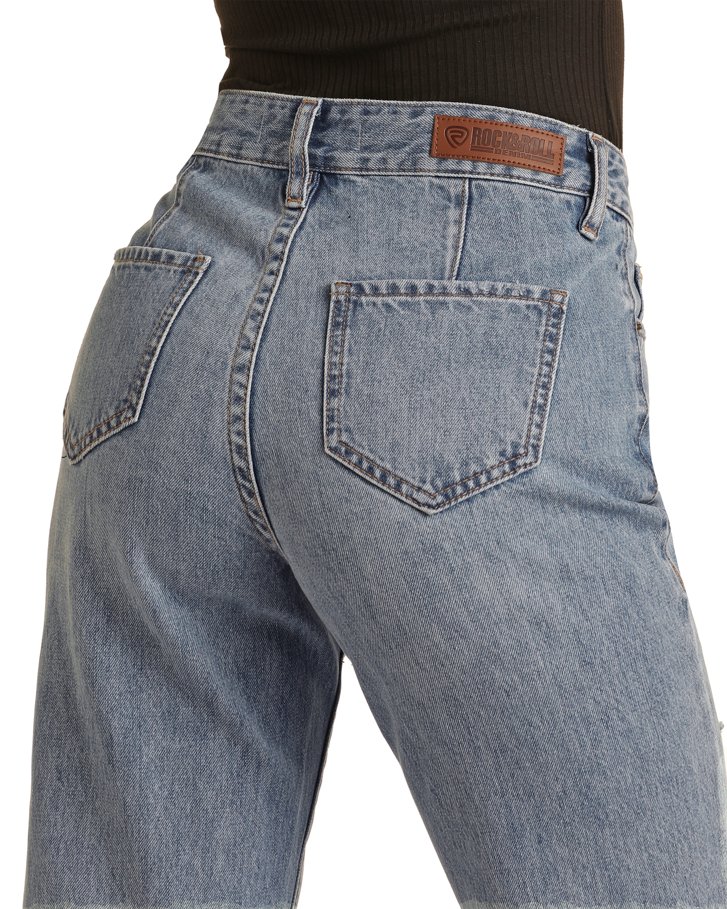 A close-up of a person wearing Rock & Roll Denim's High Rise Distressed Relaxed Wide Flare Jeans, made from 100% cotton light blue denim with two back pockets and a brown leather logo patch on the waistband.