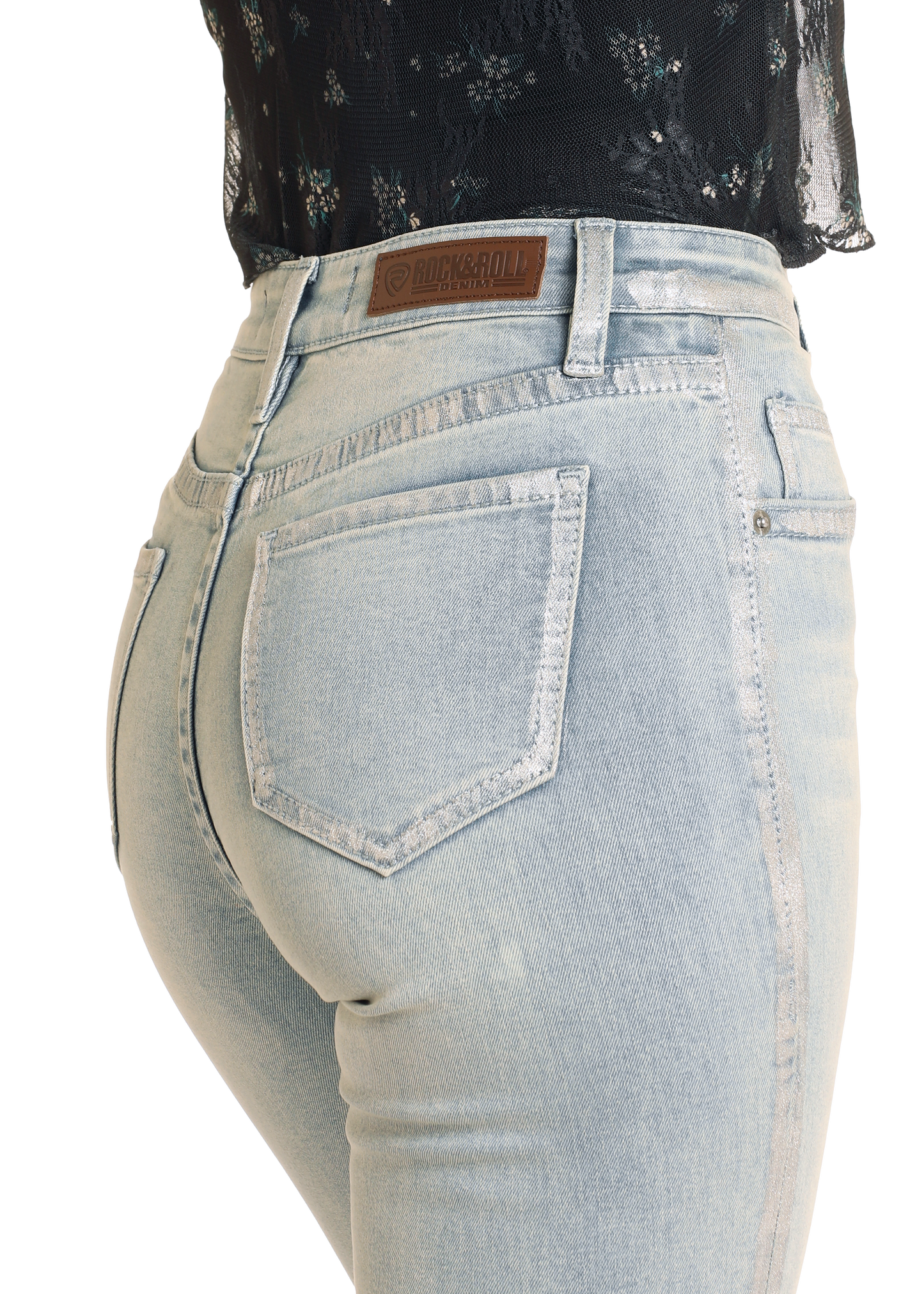 A person is shown from the waist down wearing Rock & Roll Denim High Rise Metallic Coated Flare Jeans, with the brand label visible on the waistband and paired with a black, semi-sheer floral blouse.