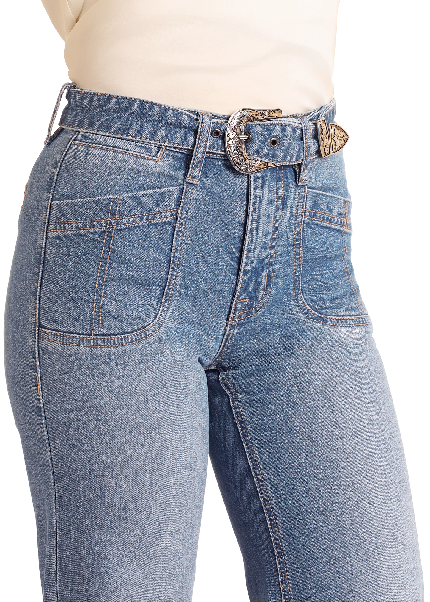 A close-up of a person wearing Rock & Roll Denim High Rise Belted Relaxed Flare Jeans with front pockets, paired with a cream top and a decorative denim Western belt with an engraved silver buckle.