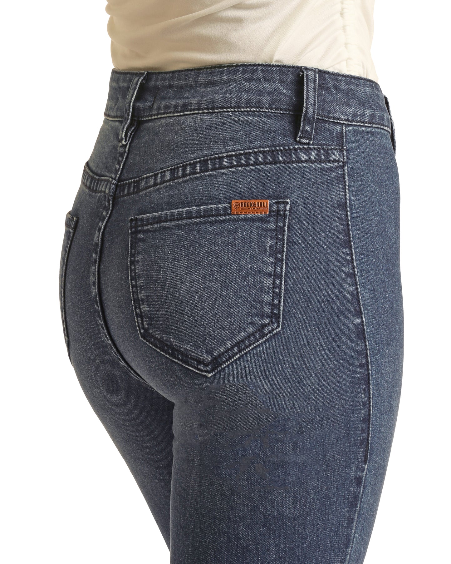 A close-up of a person wearing Rock & Roll Denim’s High Rise Classic Button Flare Jeans with a back pocket featuring a small brown label, paired with a tucked-in light-colored top.