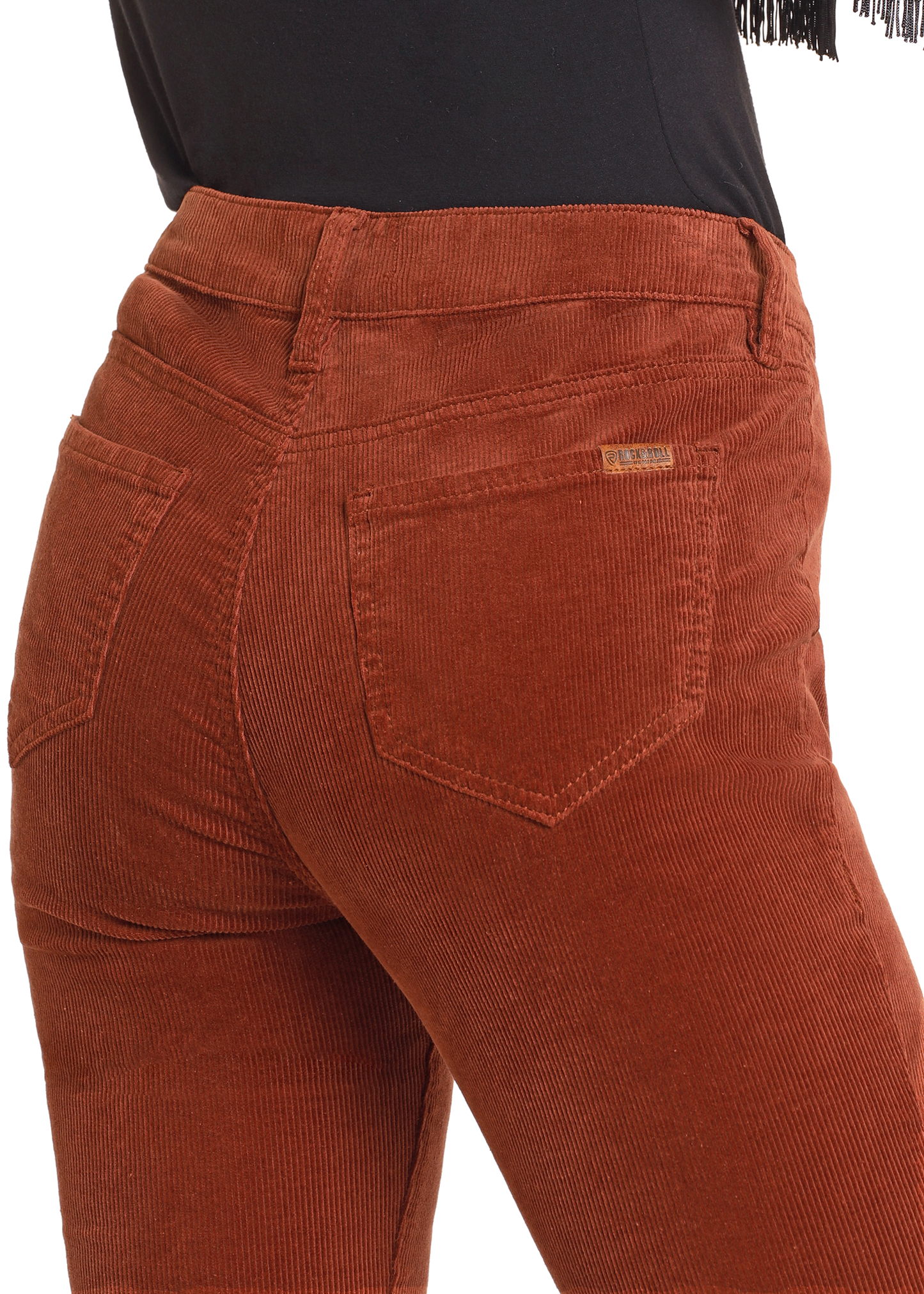 A person wears Rock & Roll Denim Rust Corduroy Button Flare Jeans, featuring a back pocket with a small rectangular label, styled with a black top.