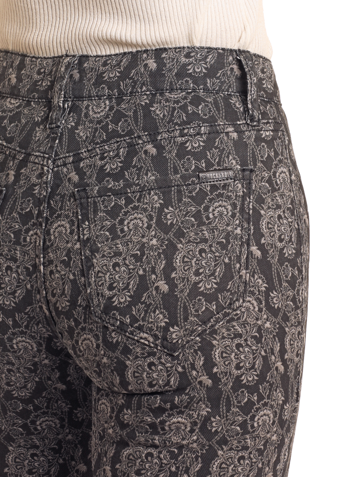 Patterned pants worn over a white sweater on a plain background